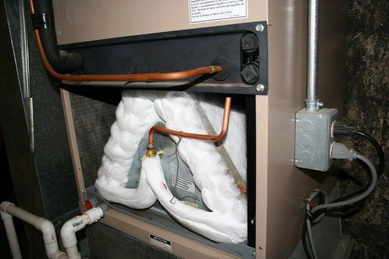 Frozen evaporator coil inside a residential air handler with heavy ice buildup on the AC coil restricting airflow.
