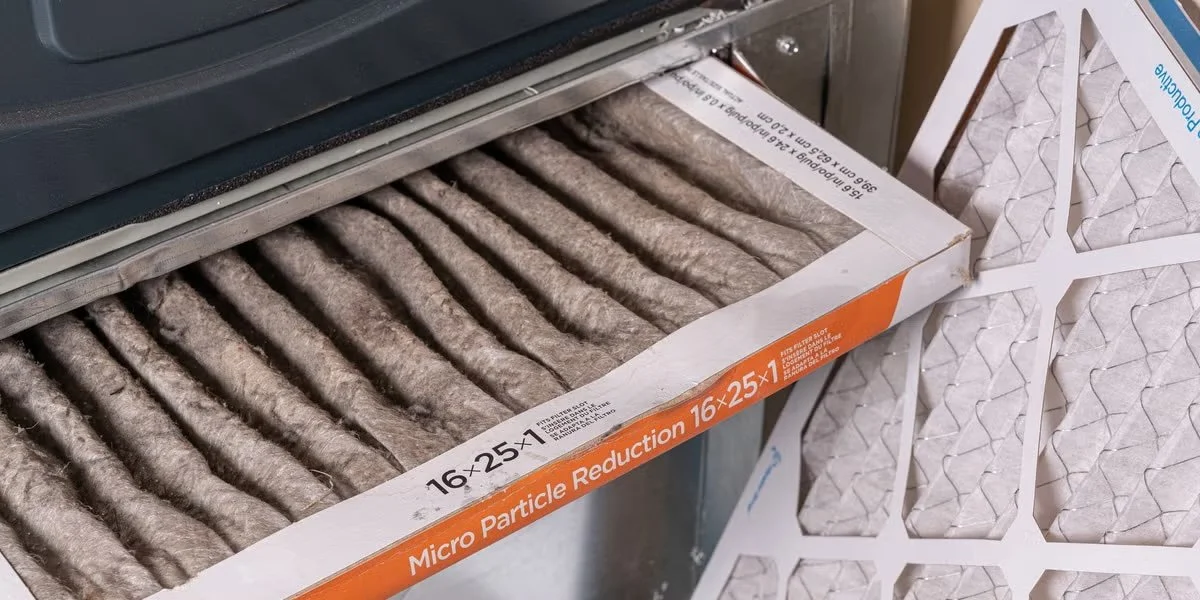 homeowner replacing a dirty air filter in HVAC system to fix AC running but not cooling problem