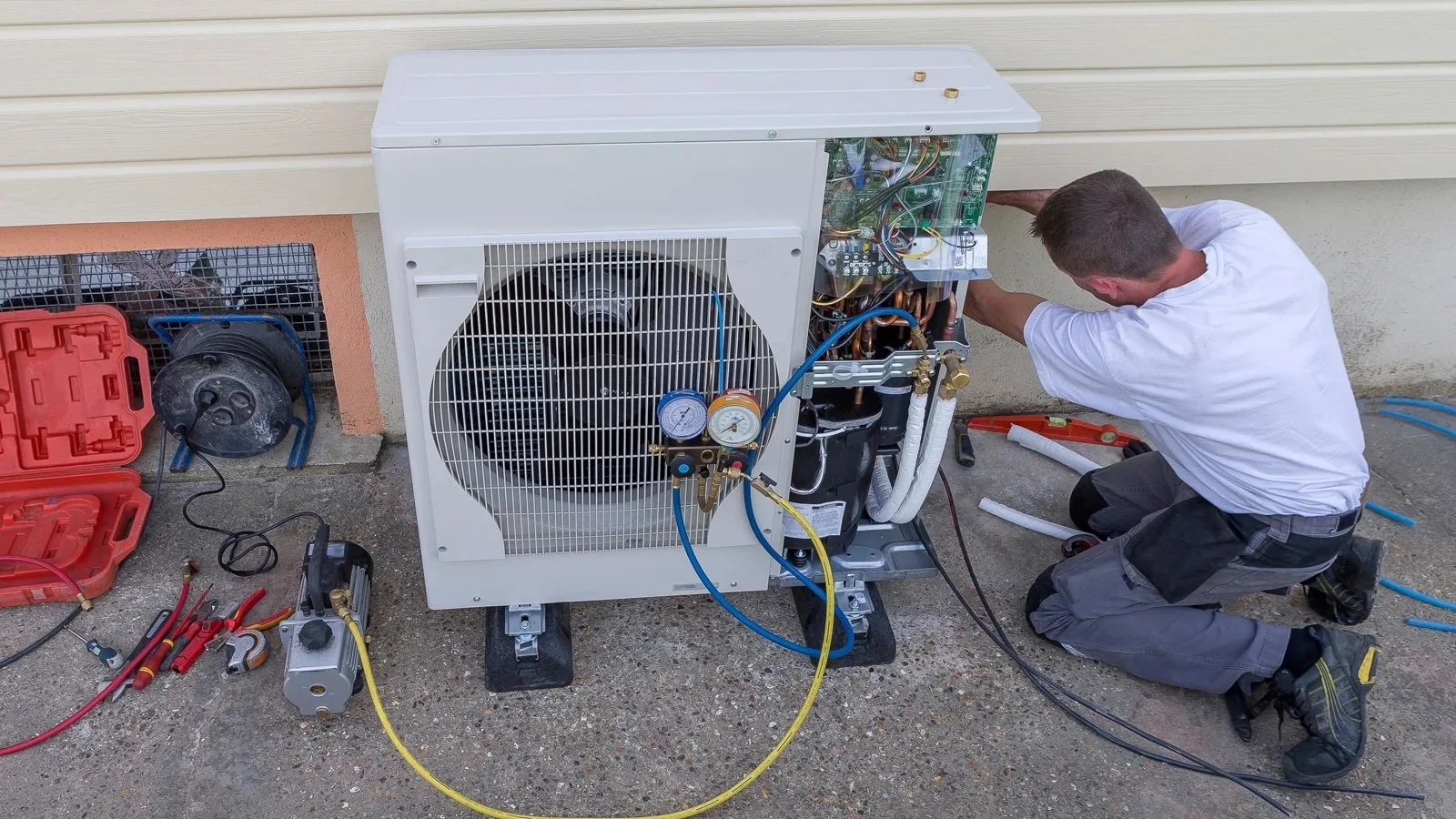 HVAC technician installing a residential heat pump condenser unit, connecting refrigerant lines and electrical components eligible for 2026 utility rebates
