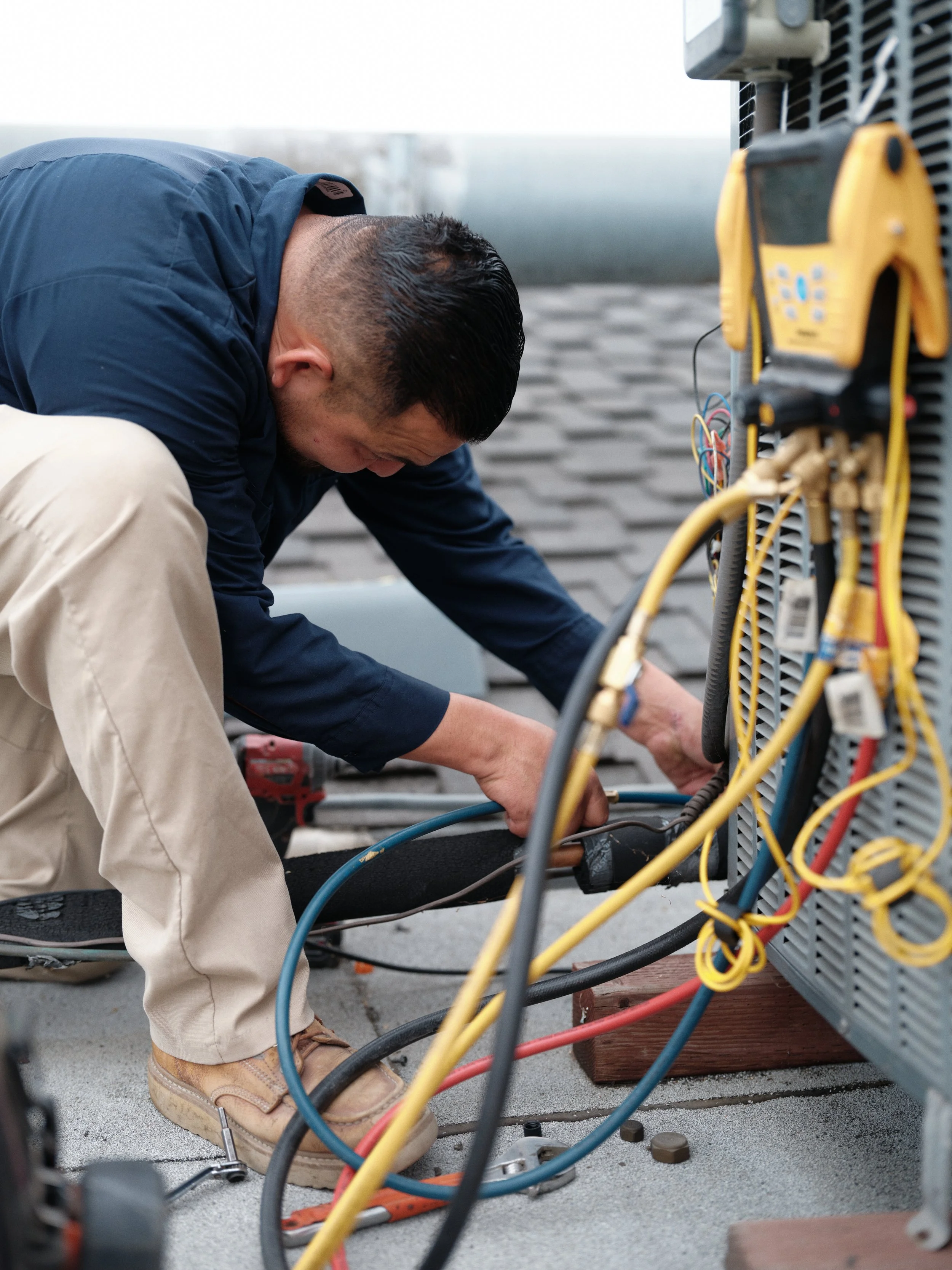 HVAC technician servicing outdoor air conditioning condenser and checking refrigerant lines to ensure proper efficiency and SEER2 performance
