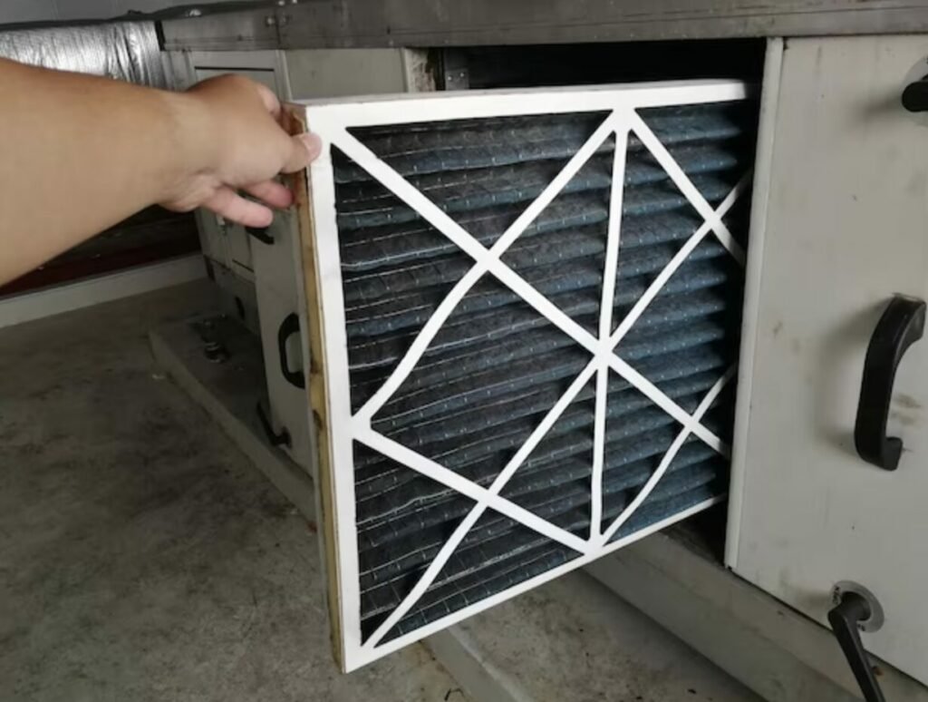 Severely clogged black HVAC air filter being removed from furnace unit during J Martin IAQ service call in Orange County