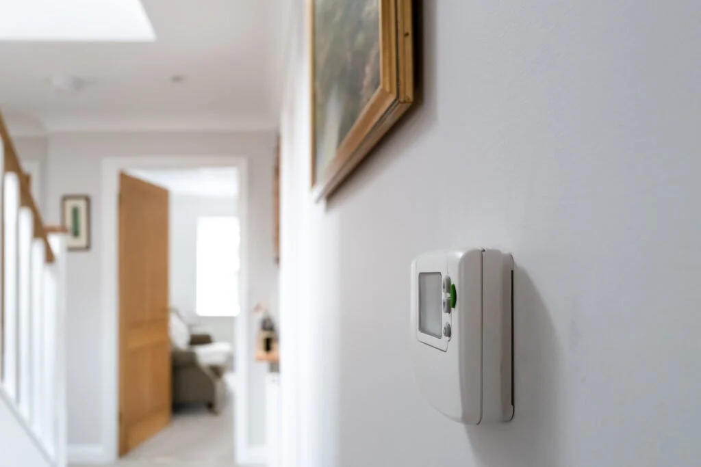 Thermostat installed on a hallway wall, which can cause inaccurate temperature readings and uneven cooling in a home