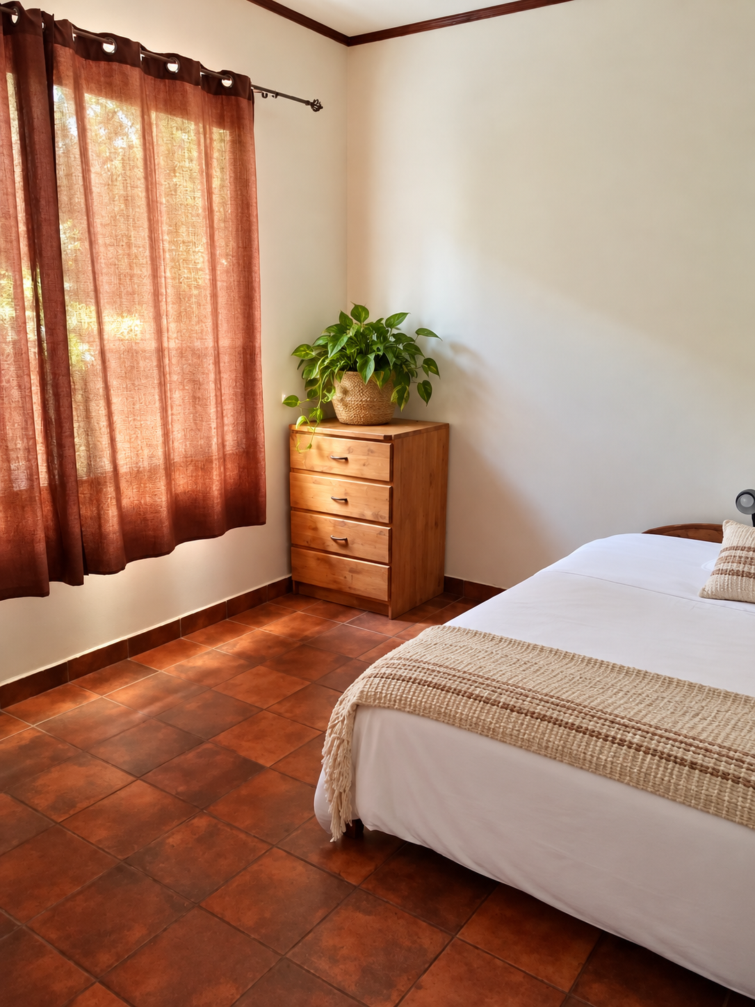 Bedroom with wooden bedside drawers, tropical plant and brown curtains at Casa Palma Bonita