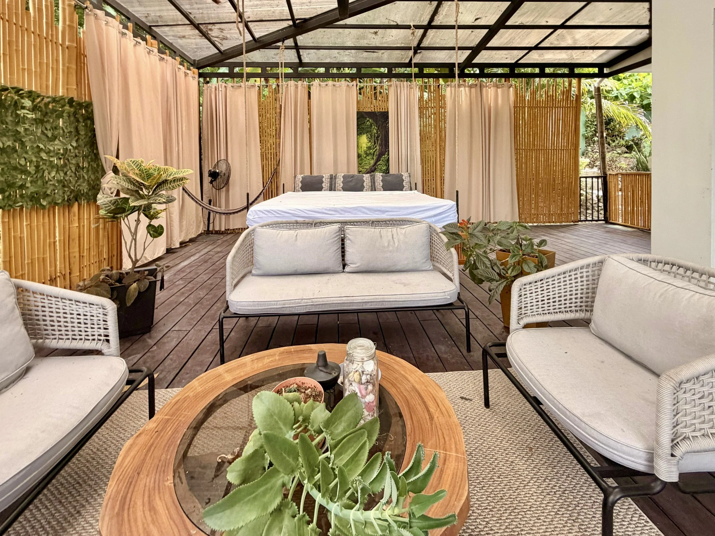 Casa Quantum covered outdoor lounge with comfortable sofas and tropical garden surroundings.