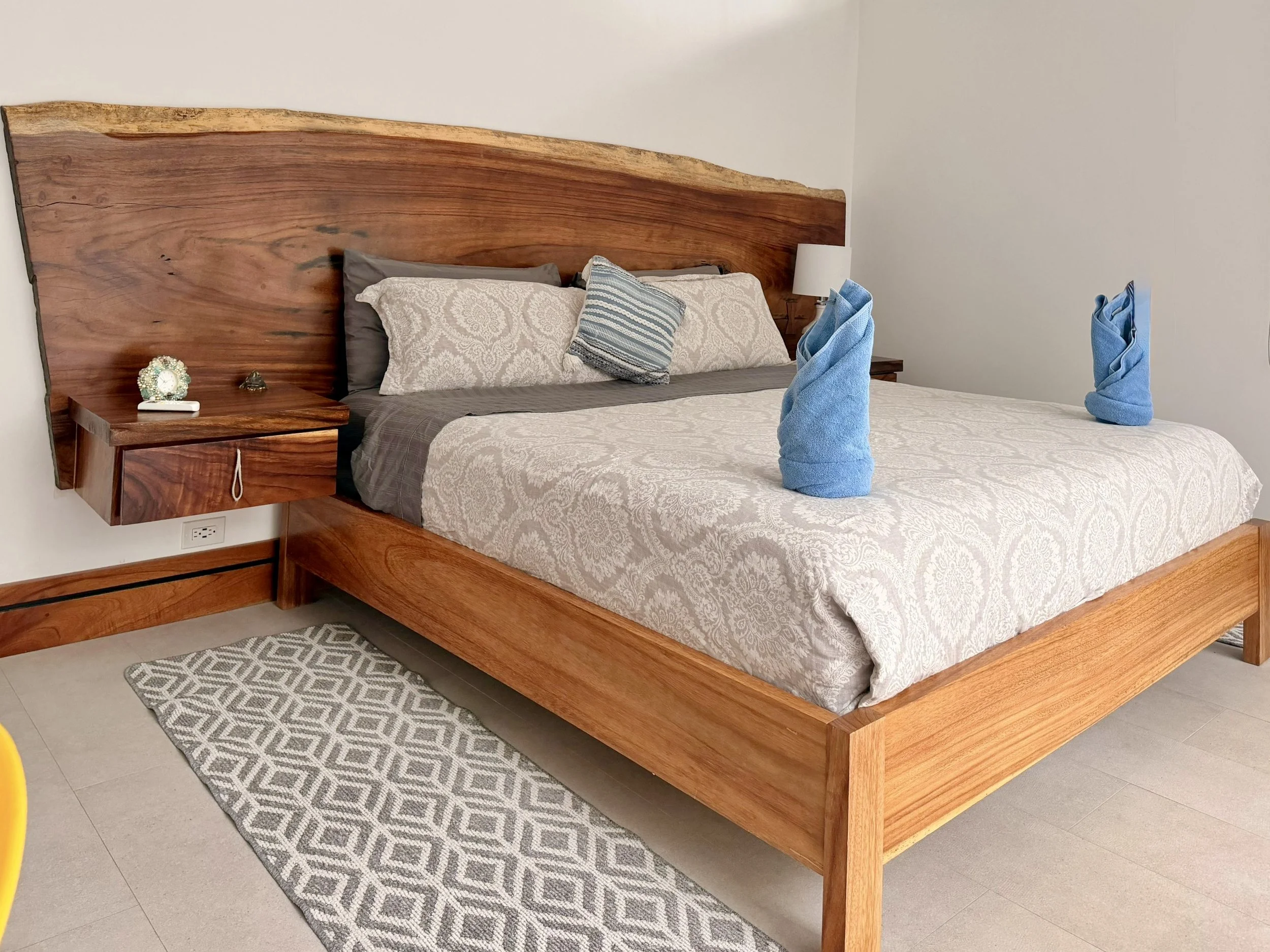 Casa Quantum furnished primary bedroom with beautiful natural wood furniture and patterned bedding in Paquera, Costa Rica.