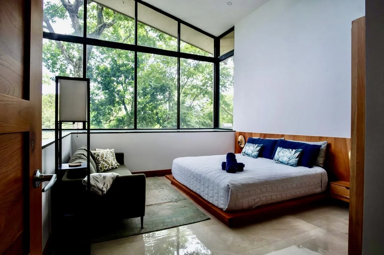 Inviting furnished bedroom with natural wood finishes, comfortable seating and tropical garden views at House of Light in Paquera, Costa Rica