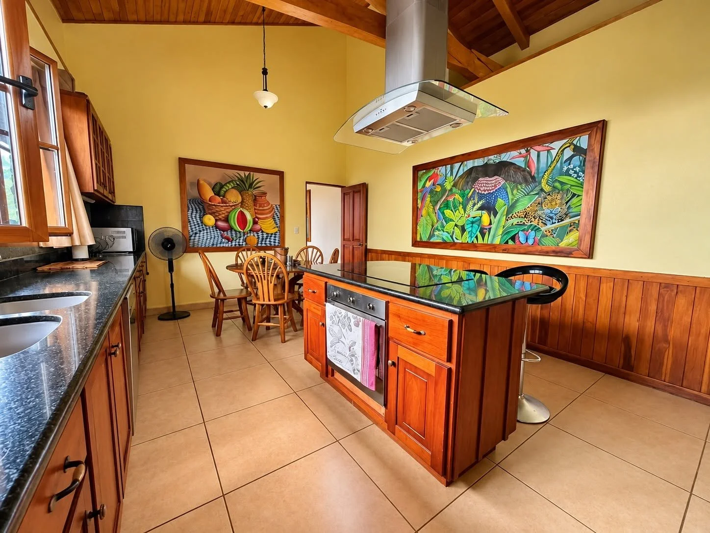 Spacious furnished kitchen with wooden cabinetry, central island and vaulted ceiling at Finca Pamela