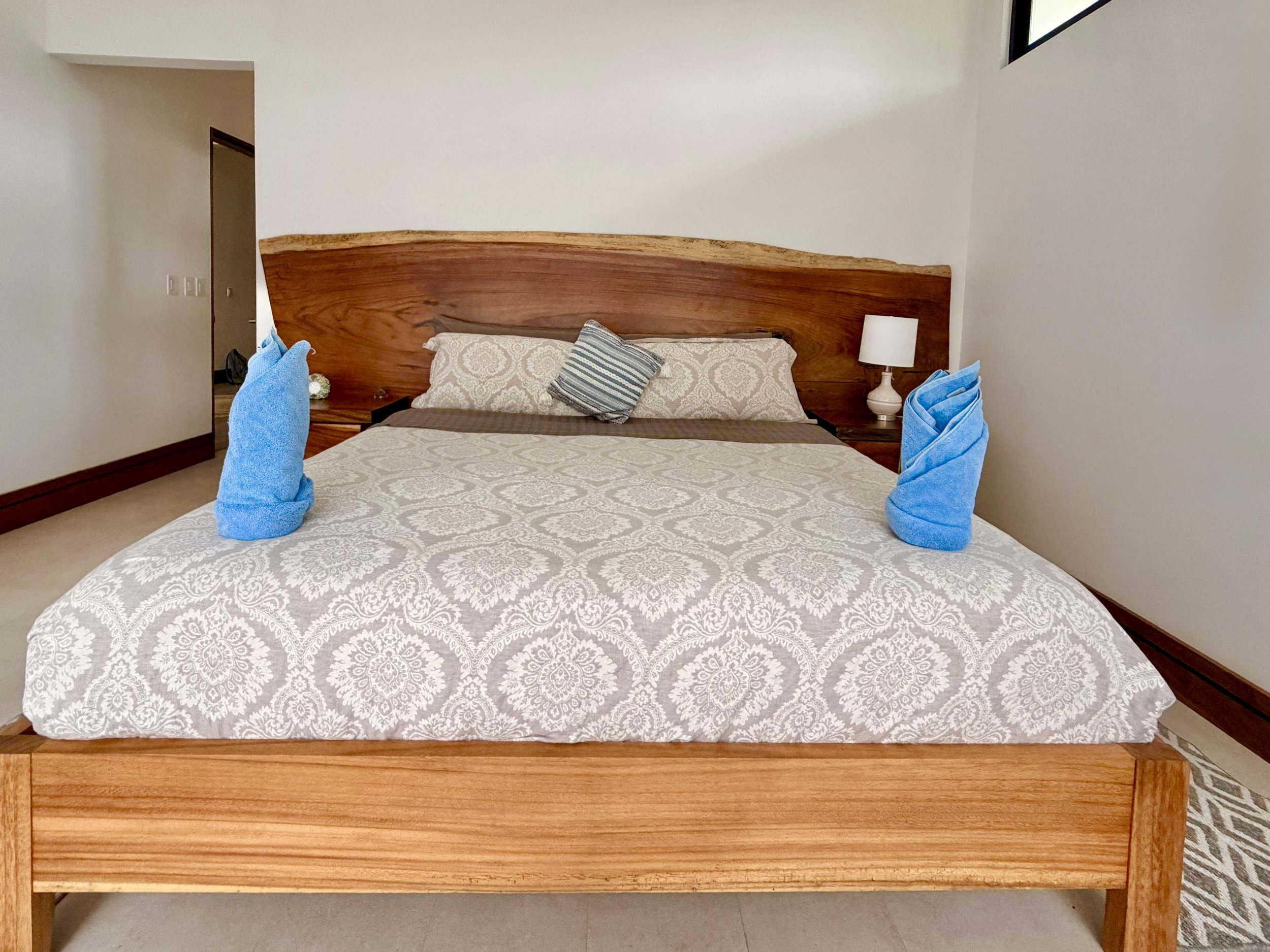 Casa Quantum primary bedroom featuring a handcrafted wooden bed frame, decorative pillows and custom wood headboard.