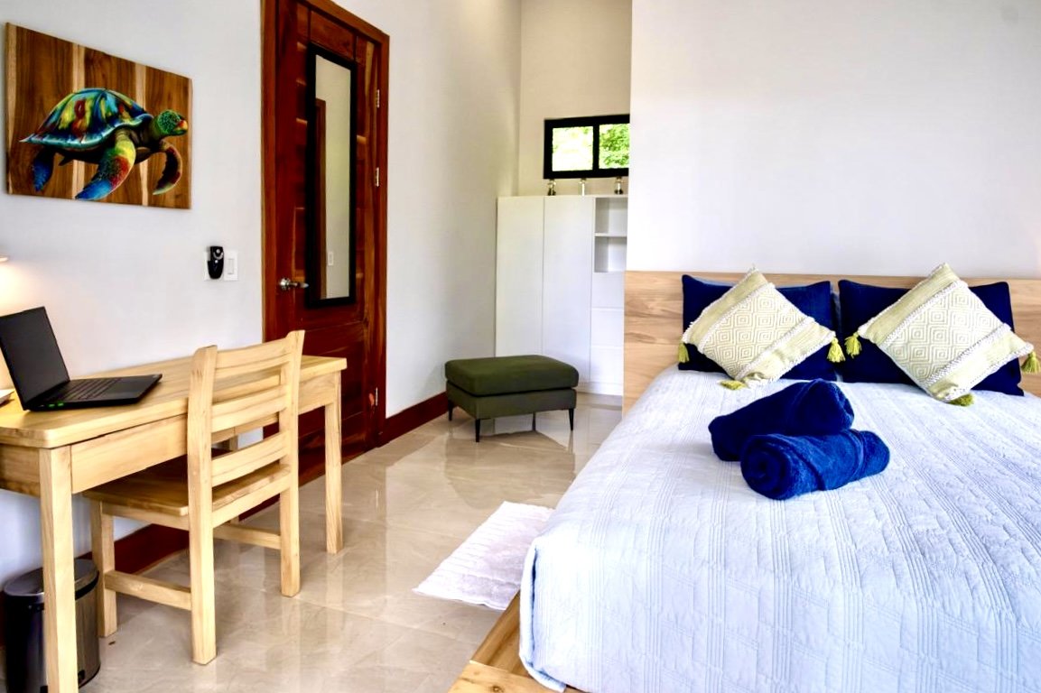 Comfortable furnished bedroom with wooden bed, dedicated workspace and modern tropical decor at House of Light in Paquera, Costa Rica