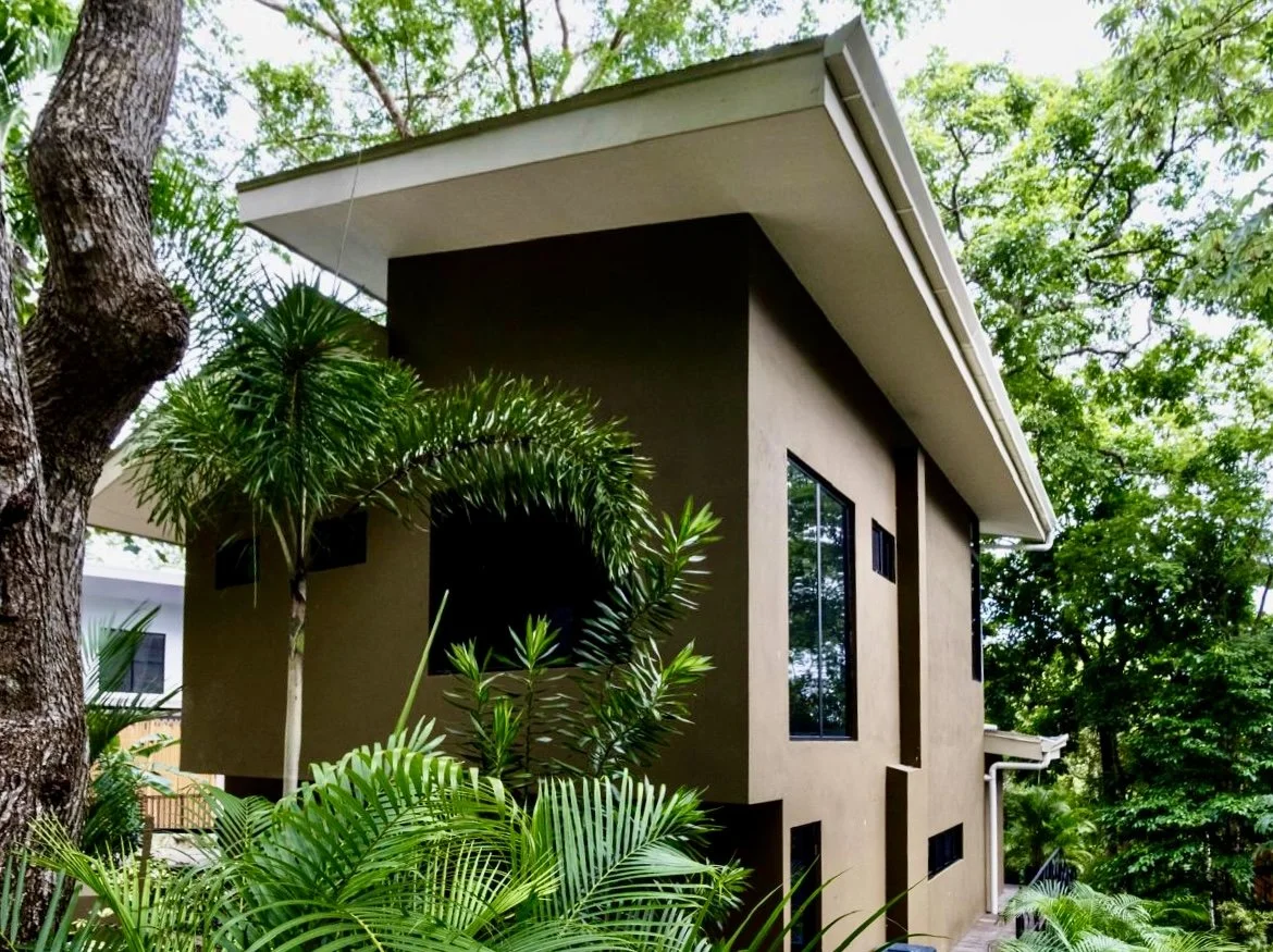 Side exterior of House of Light featuring contemporary tropical architecture, large windows and lush landscaping in Paquera, Costa Rica
