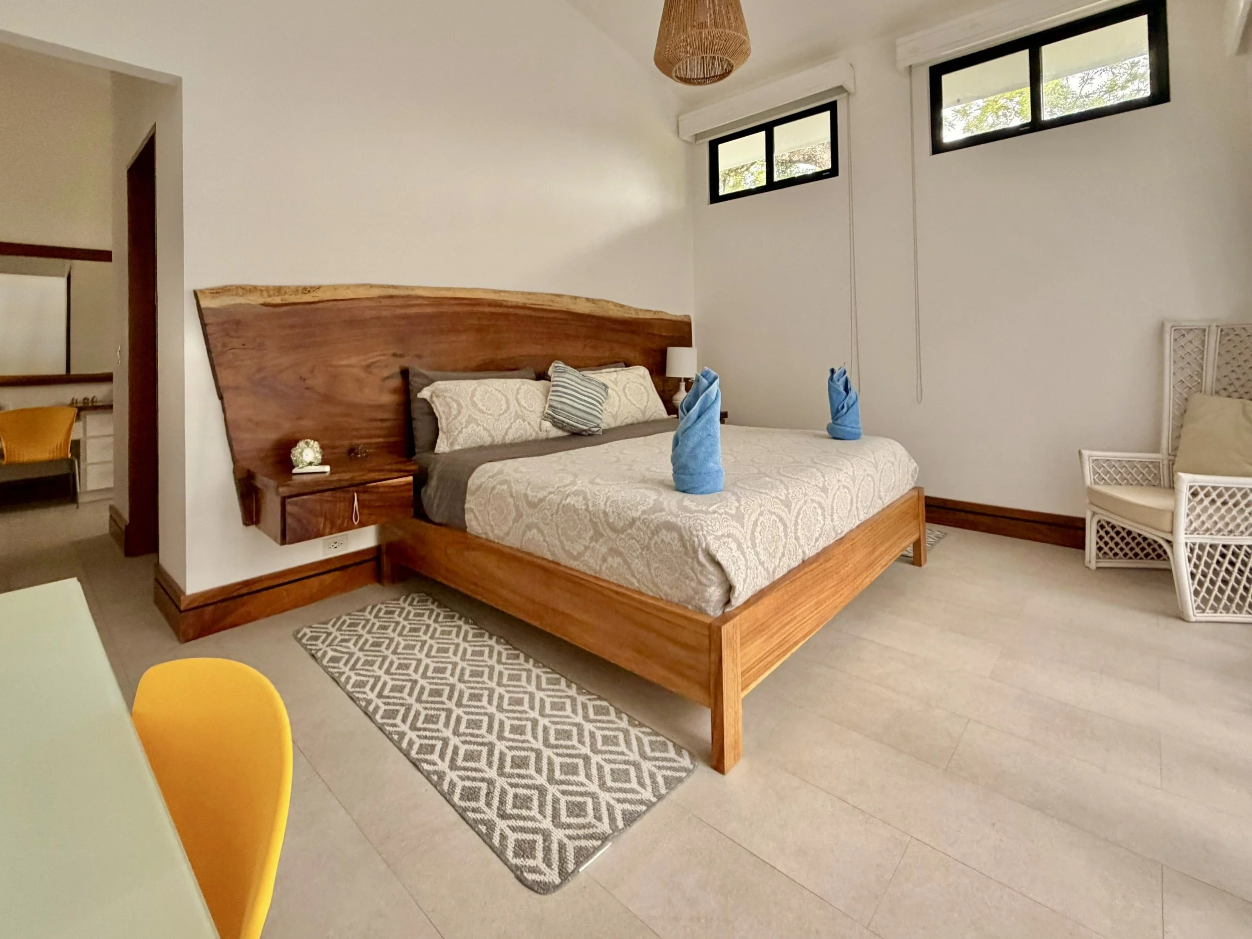 Casa Quantum primary bedroom with custom Guanacaste wood headboard, king-size style bed and modern tropical decor.