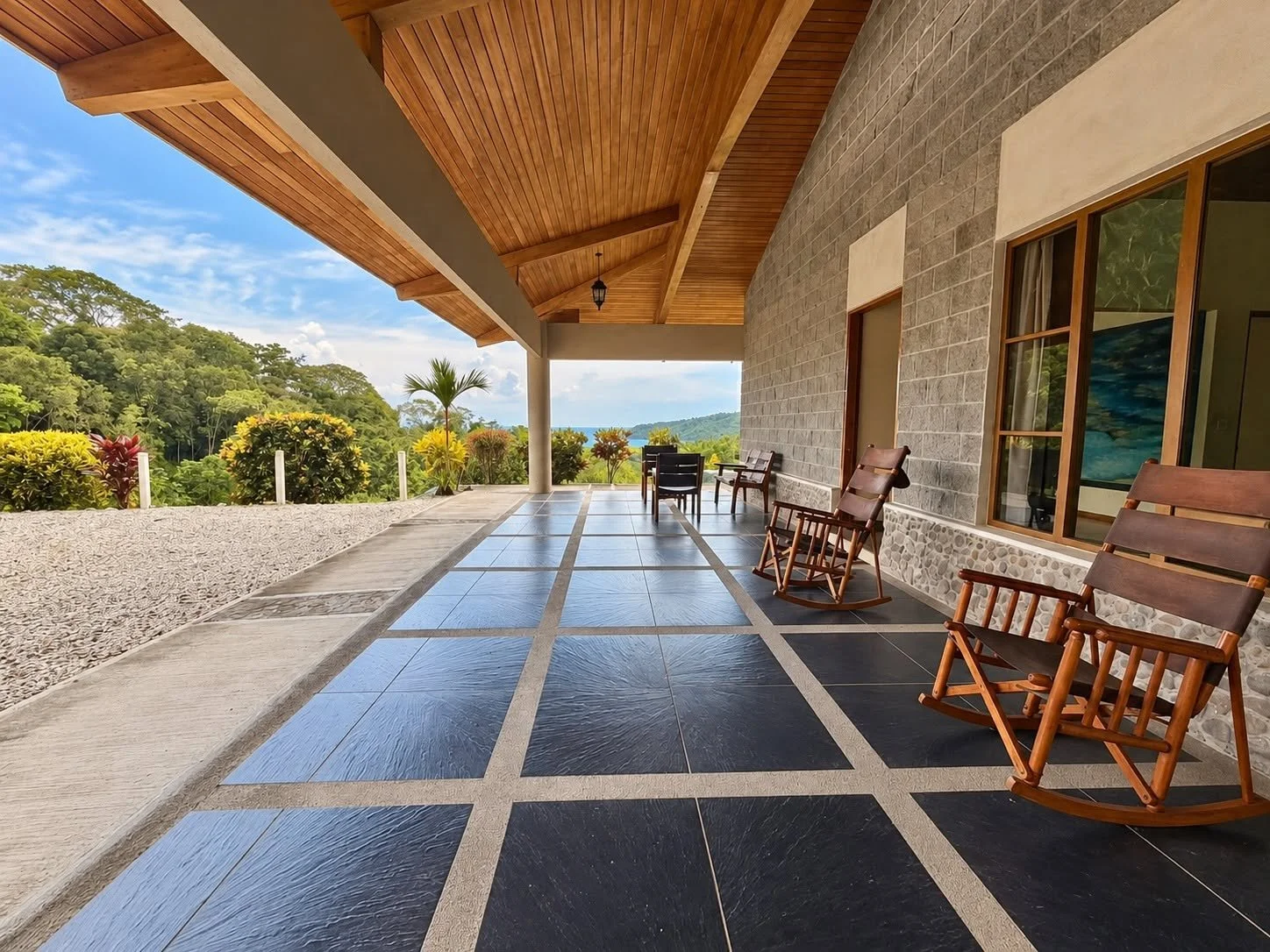 Expansive covered terrace with rocking chairs and tropical landscape views at Finca Pamela