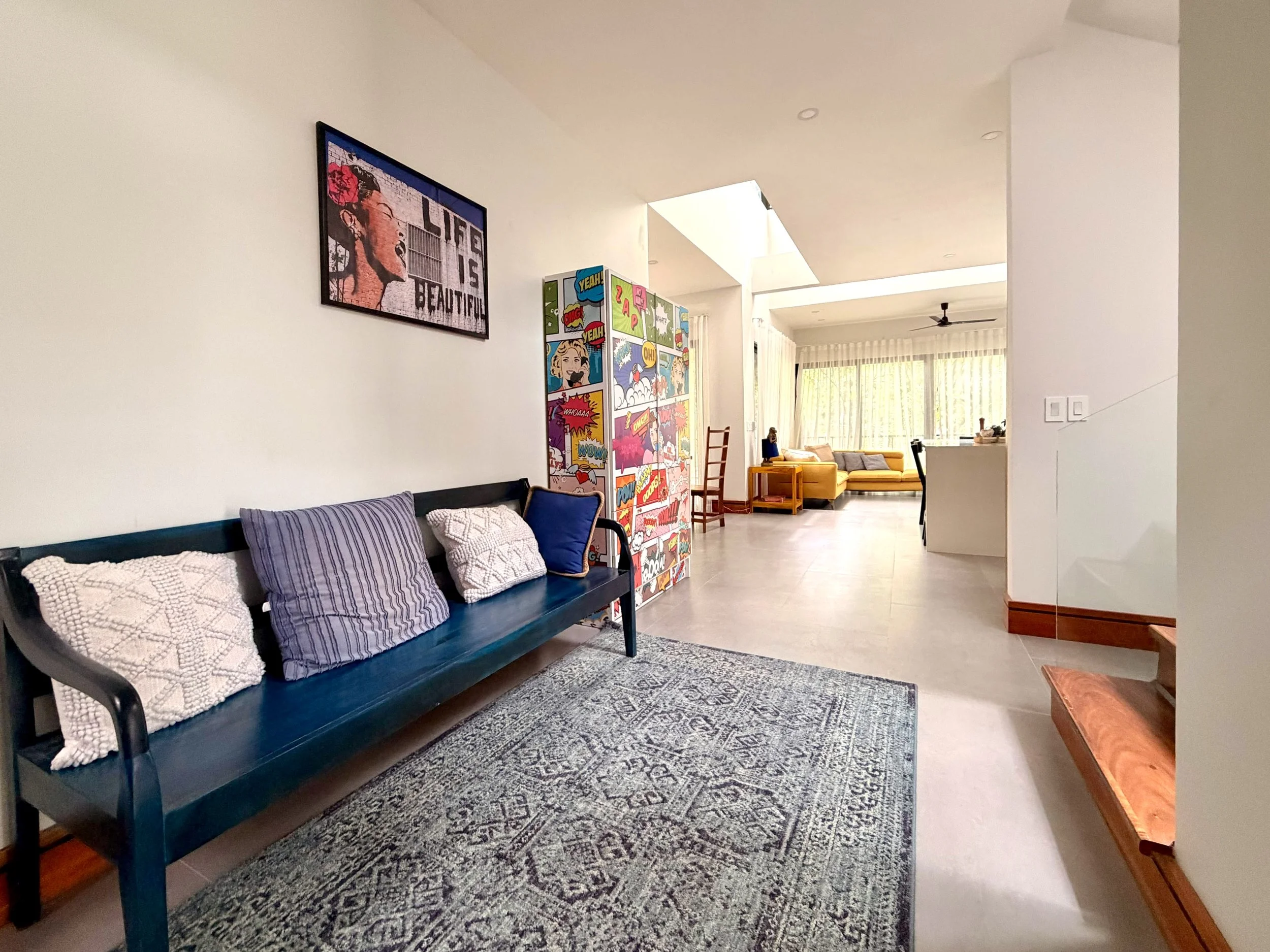 Casa Colina comfortable lounge with blue sofa, colorful artwork and open-plan living space.