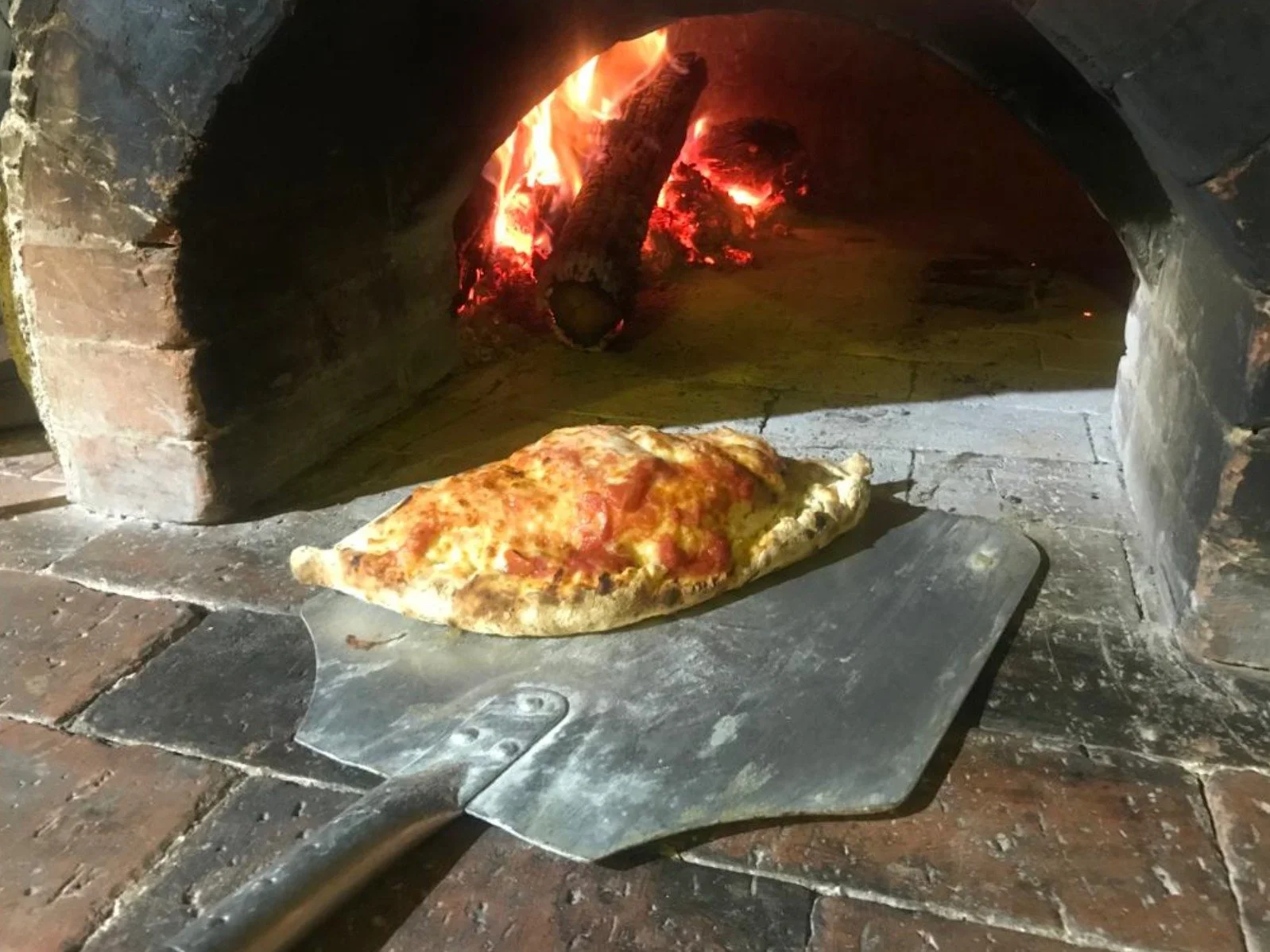 Pizza baking inside a traditional wood-fired oven at established restaurant for sale in Tambor, Costa Rica.