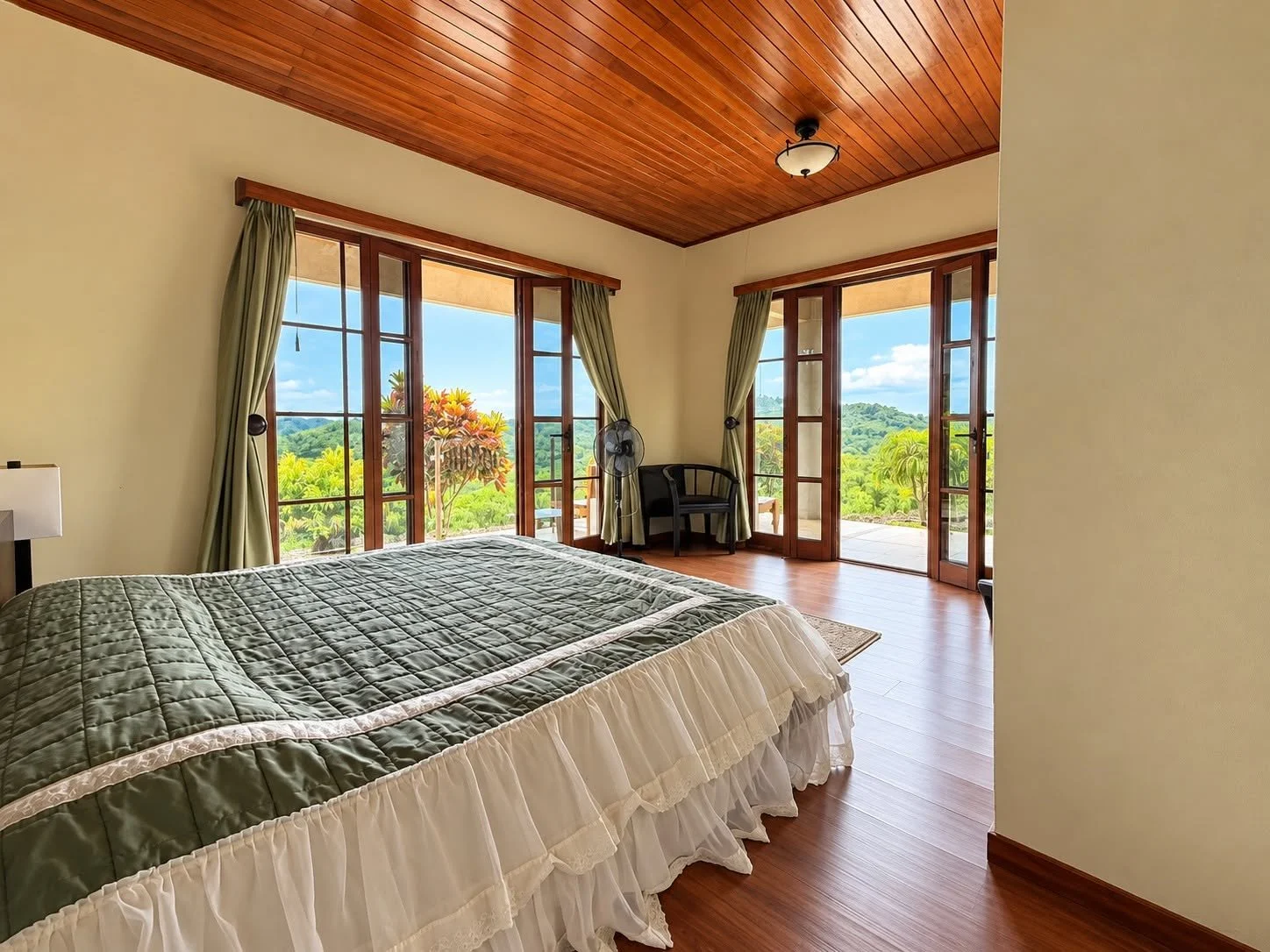 Spacious bedroom with wood ceiling, balcony access and tropical views at Finca Pamela