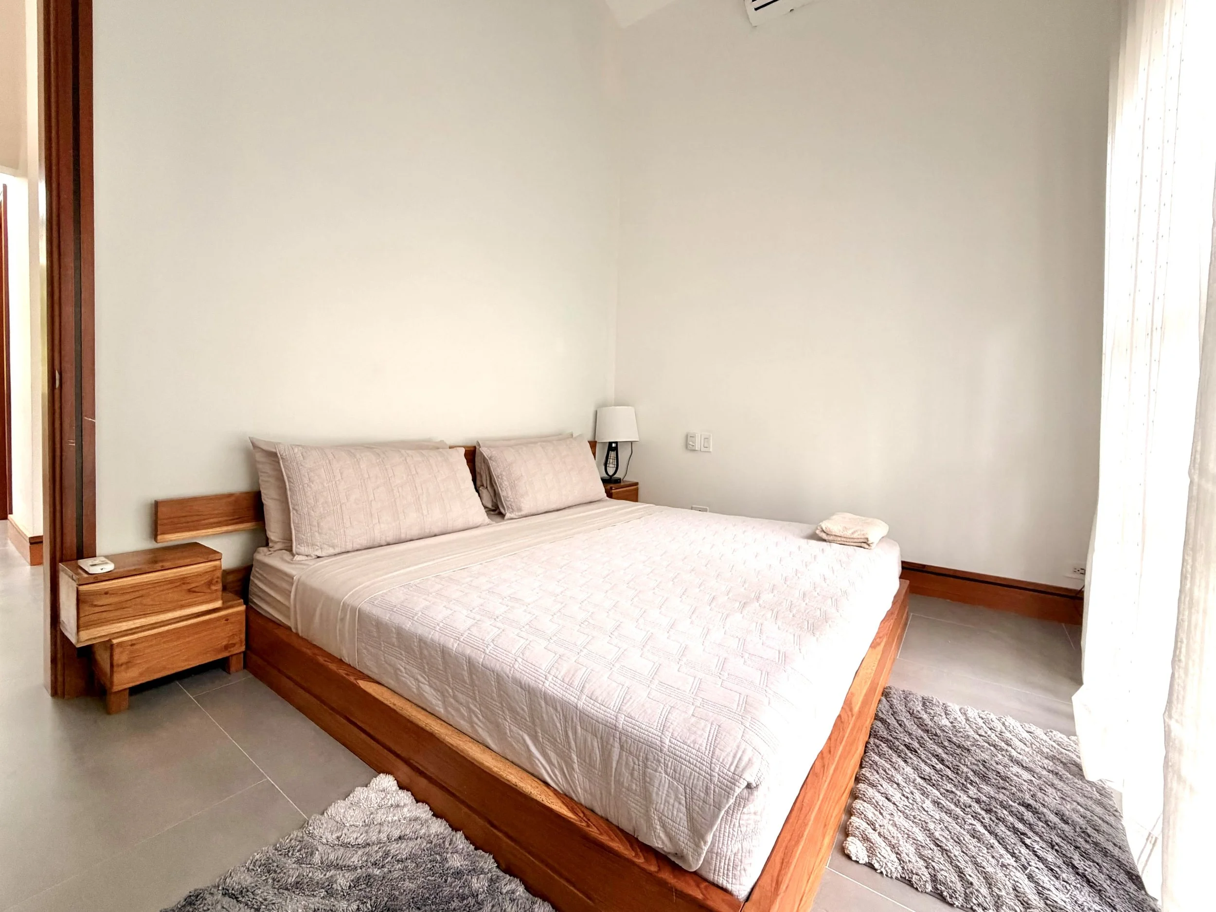 Casa Colina furnished upstairs bedroom with wooden platform bed, neutral bedding and contemporary finishes.