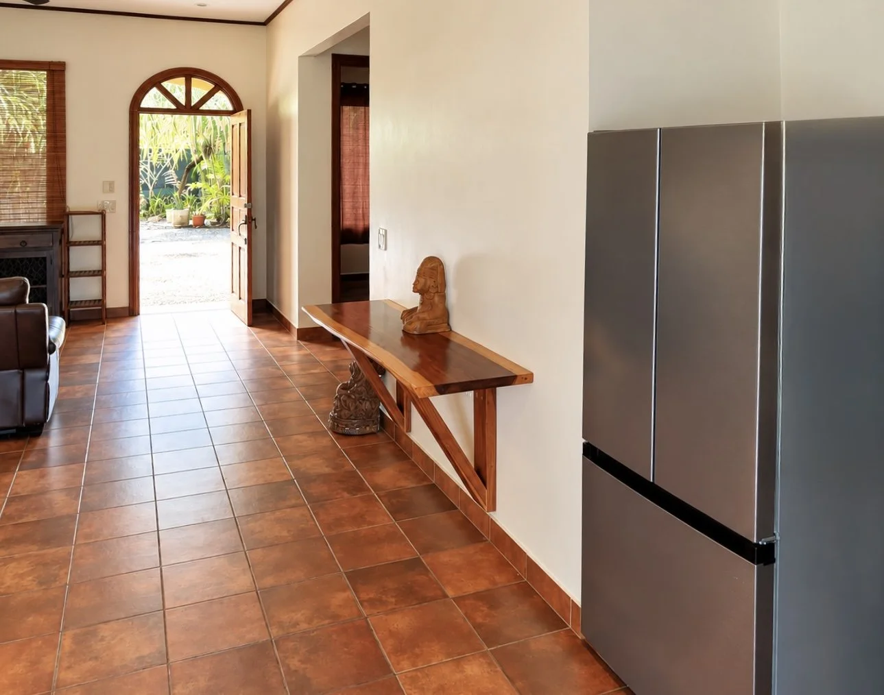 Bright interior hallway with terracotta tile floors, wooden console and front entrance at Casa Palma Bonita