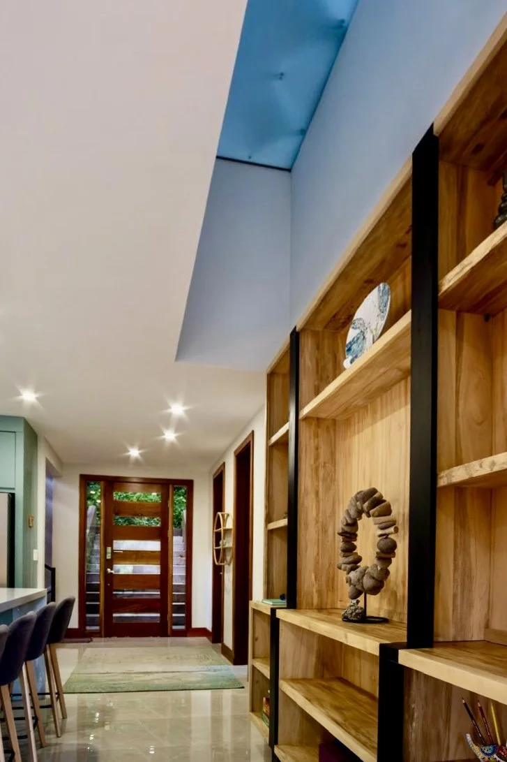 Bright interior hallway with custom-built wooden shelving, decorative finishes and polished floors at House of Light in Paquera, Costa Rica