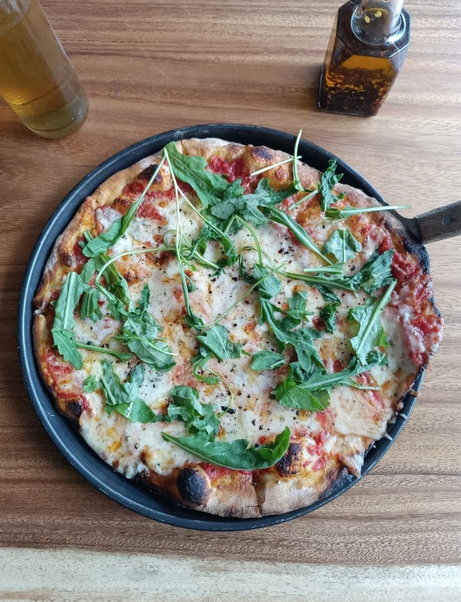 Freshly prepared gourmet pizza with vegetables and cheese from established pizzeria in Tambor, Costa Rica.