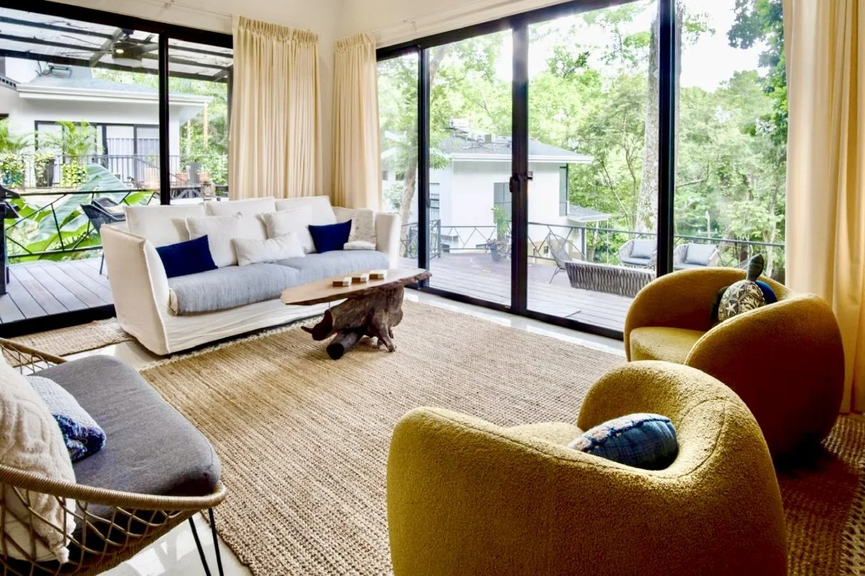 Bright tropical living room with comfortable seating, floor-to-ceiling sliding glass doors and garden views at House of Light in Paquera, Costa Rica
