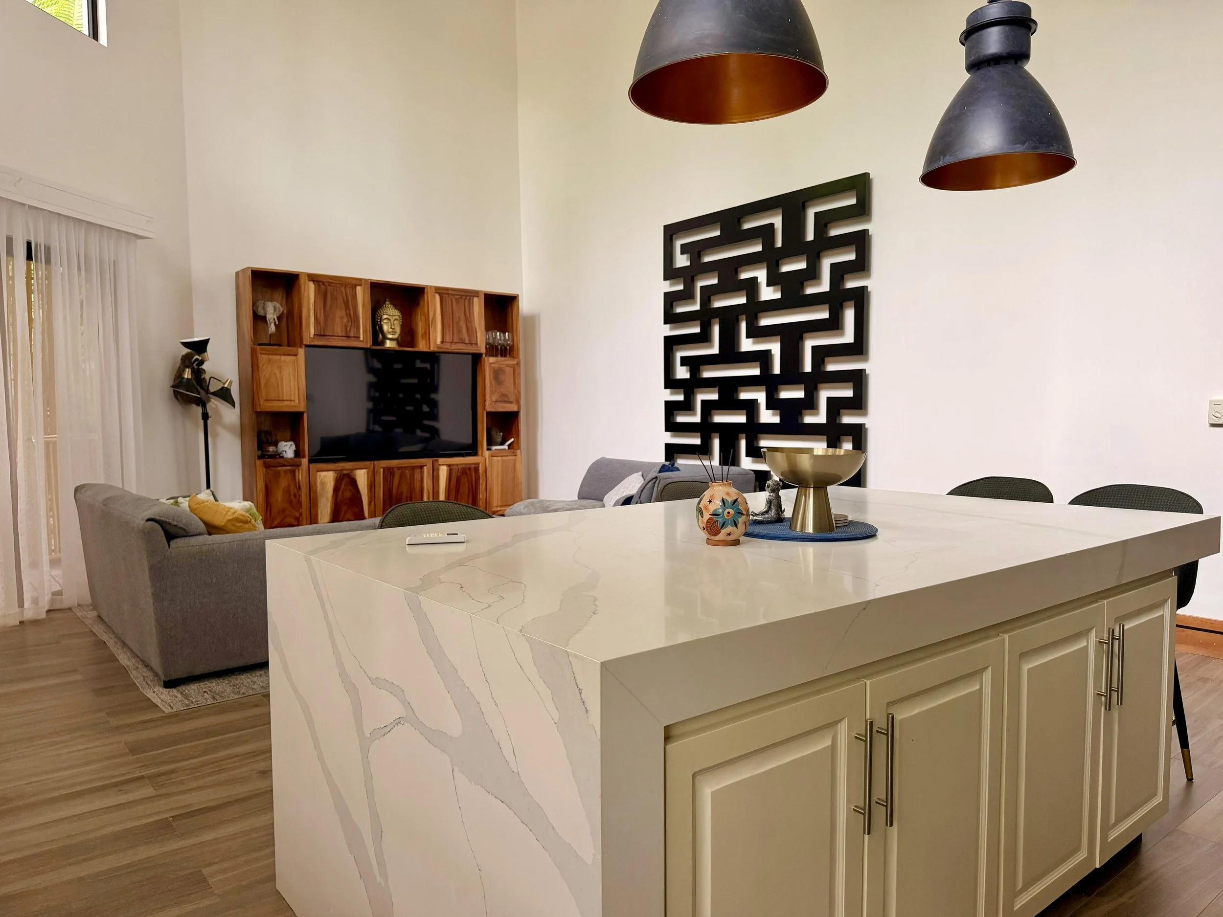 Casa Quantum elegant quartz kitchen island with pendant lights and adjoining furnished living area.