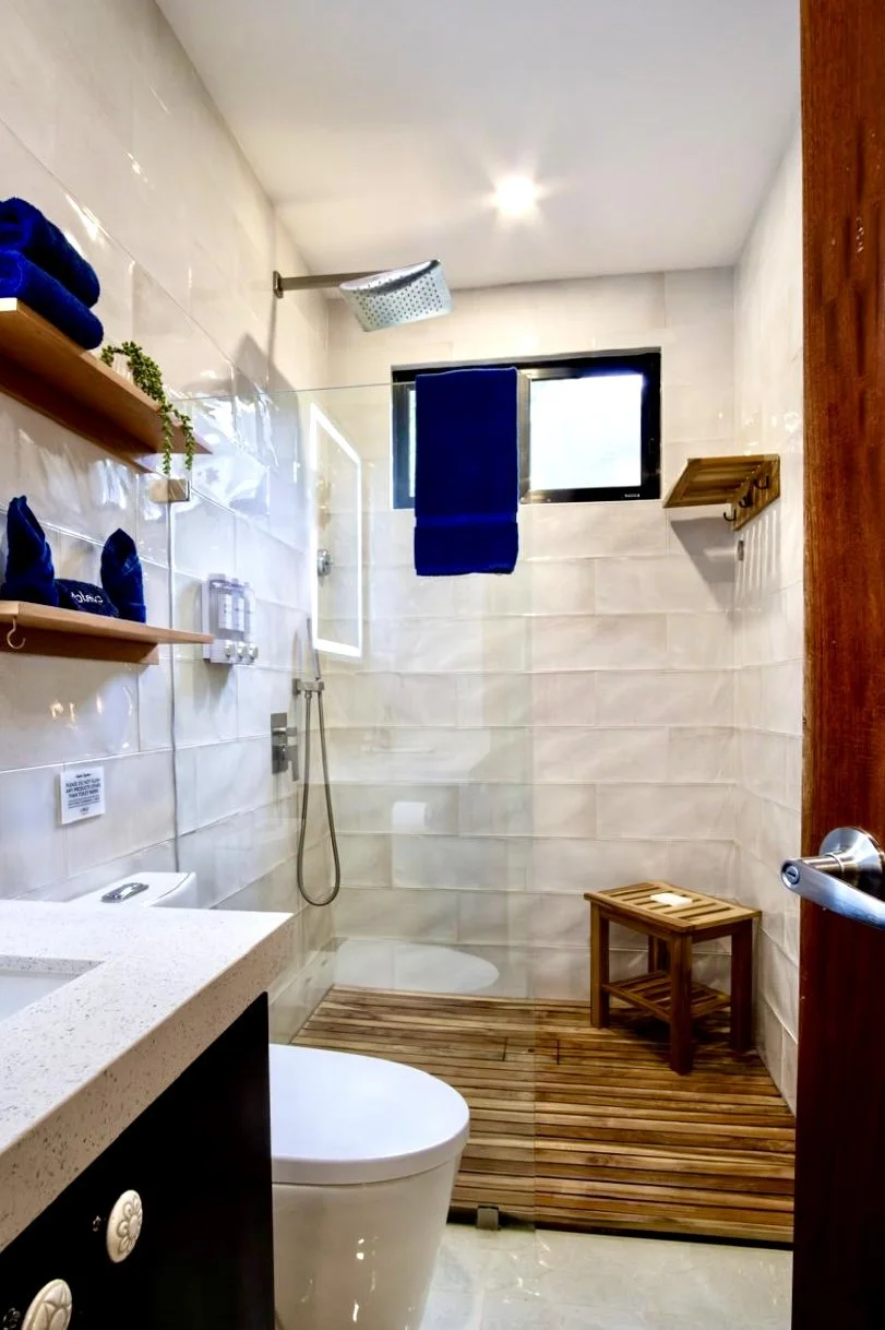 Modern bathroom with rainfall walk-in shower, white tiled walls and natural wood accents at House of Light in Paquera, Costa Rica