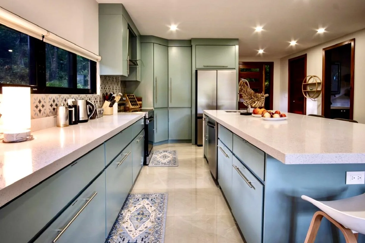 Modern fully equipped kitchen with custom green cabinetry, quartz countertops and stainless steel appliances at House of Light in Paquera, Costa Rica