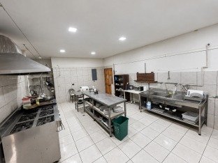 Spacious tiled commercial kitchen with stainless steel counters and food preparation areas at Tambor restaurant.