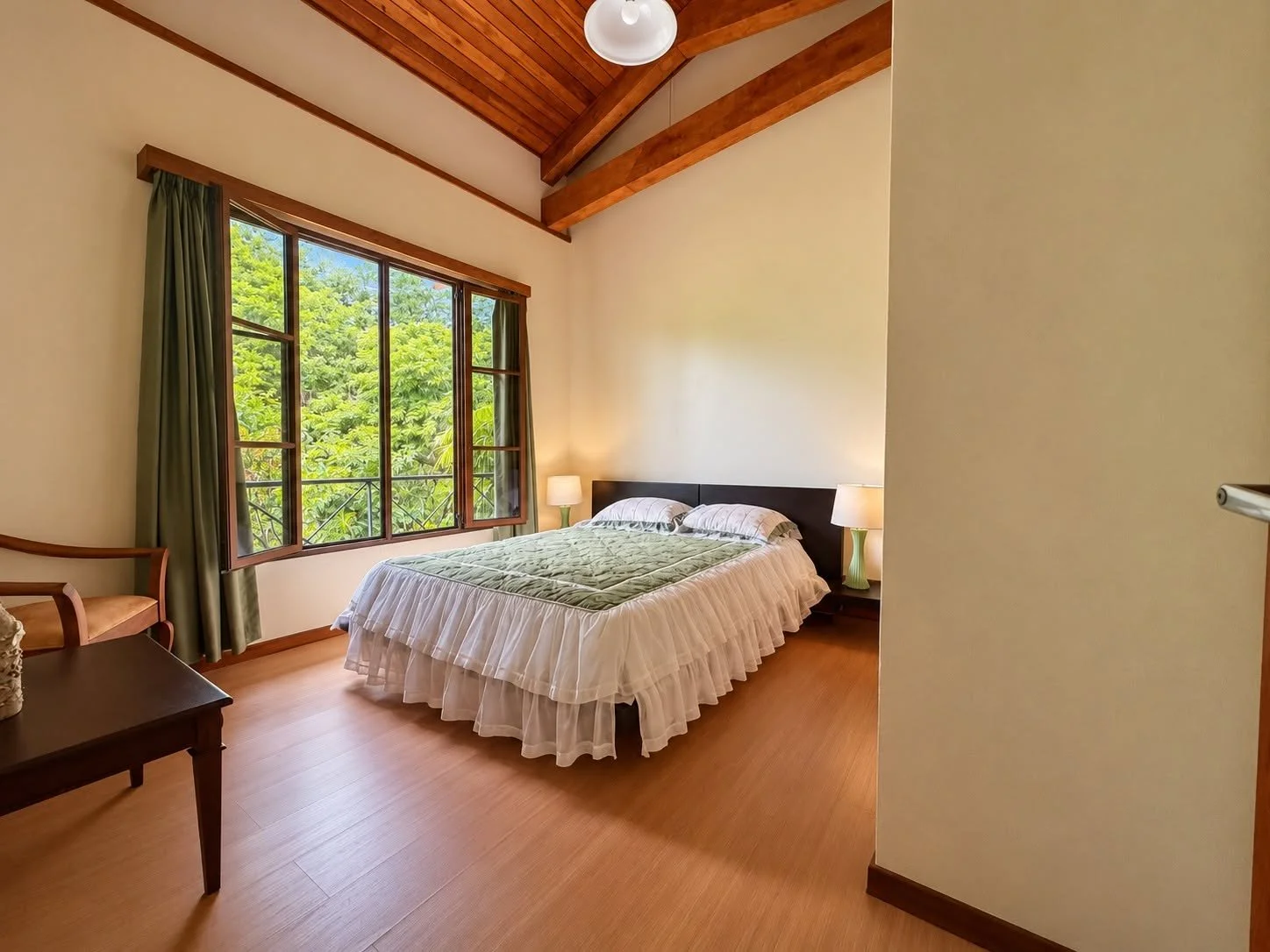 Furnished bedroom with large window overlooking tropical gardens at Finca Pamela
