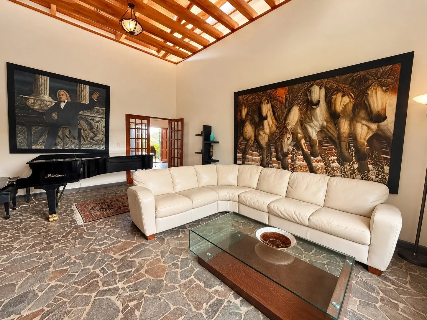 Elegant living room with Blüthner grand piano, vaulted wooden ceiling and stone flooring at Finca Pamela