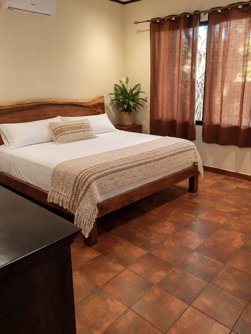 Main bedroom at Casa Palma Bonita with wooden bed frame, white bedding and terracotta tile floors