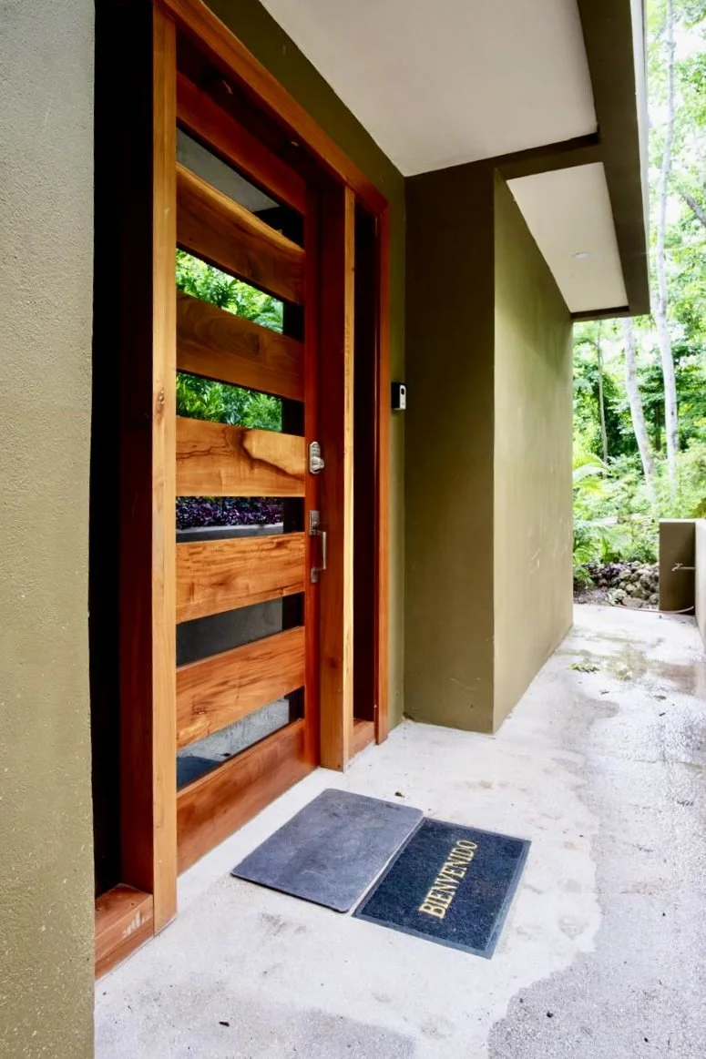 Custom wooden entrance door with glass panels and natural wood finishes at House of Light tropical home in Paquera, Costa Rica
