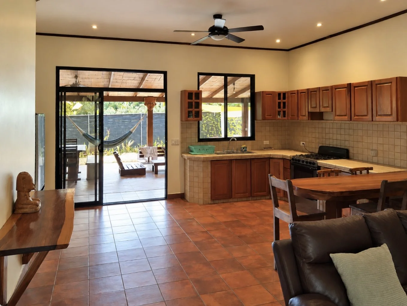 Open-plan kitchen and living area with hardwood cabinetry and terracotta floors at Casa Palma Bonita