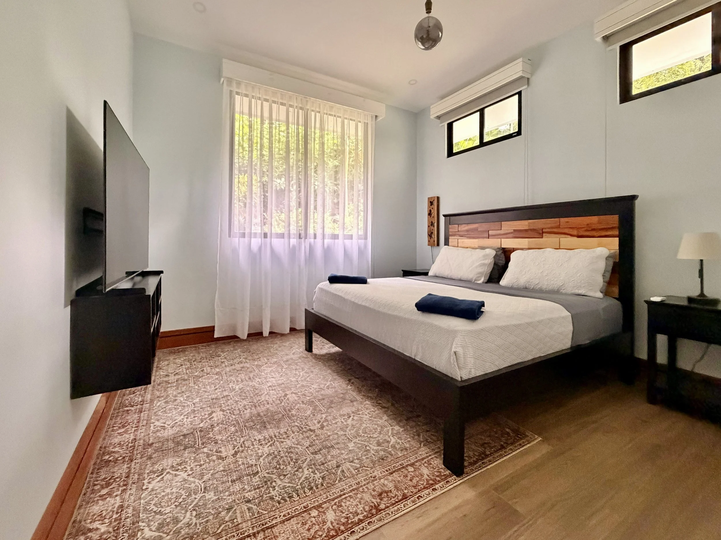 Casa Quantum second bedroom with comfortable bed, natural light and tropical garden views through the window.