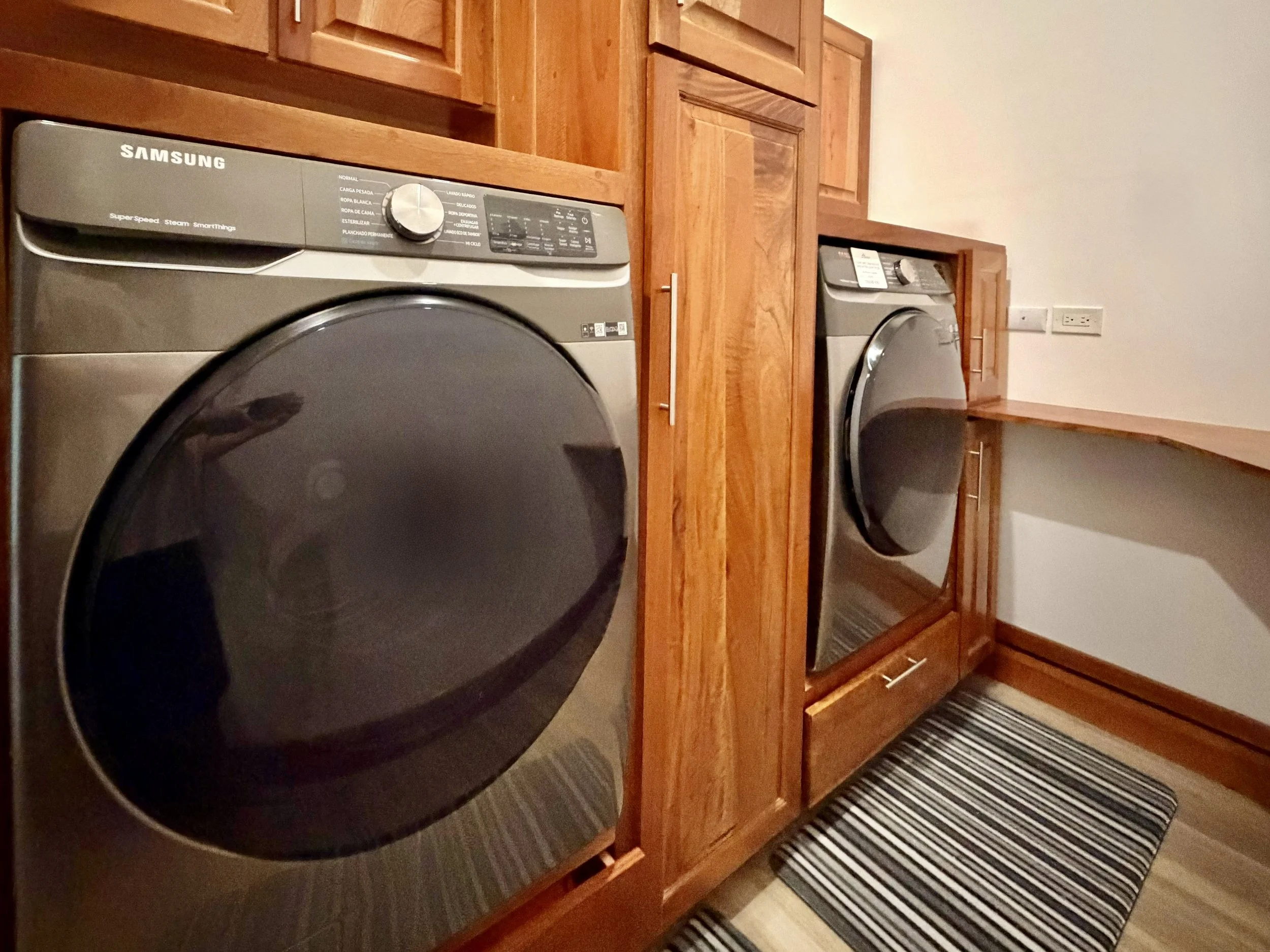 Casa Quantum laundry area with front-loading washer and dryer built into custom wooden cabinetry.