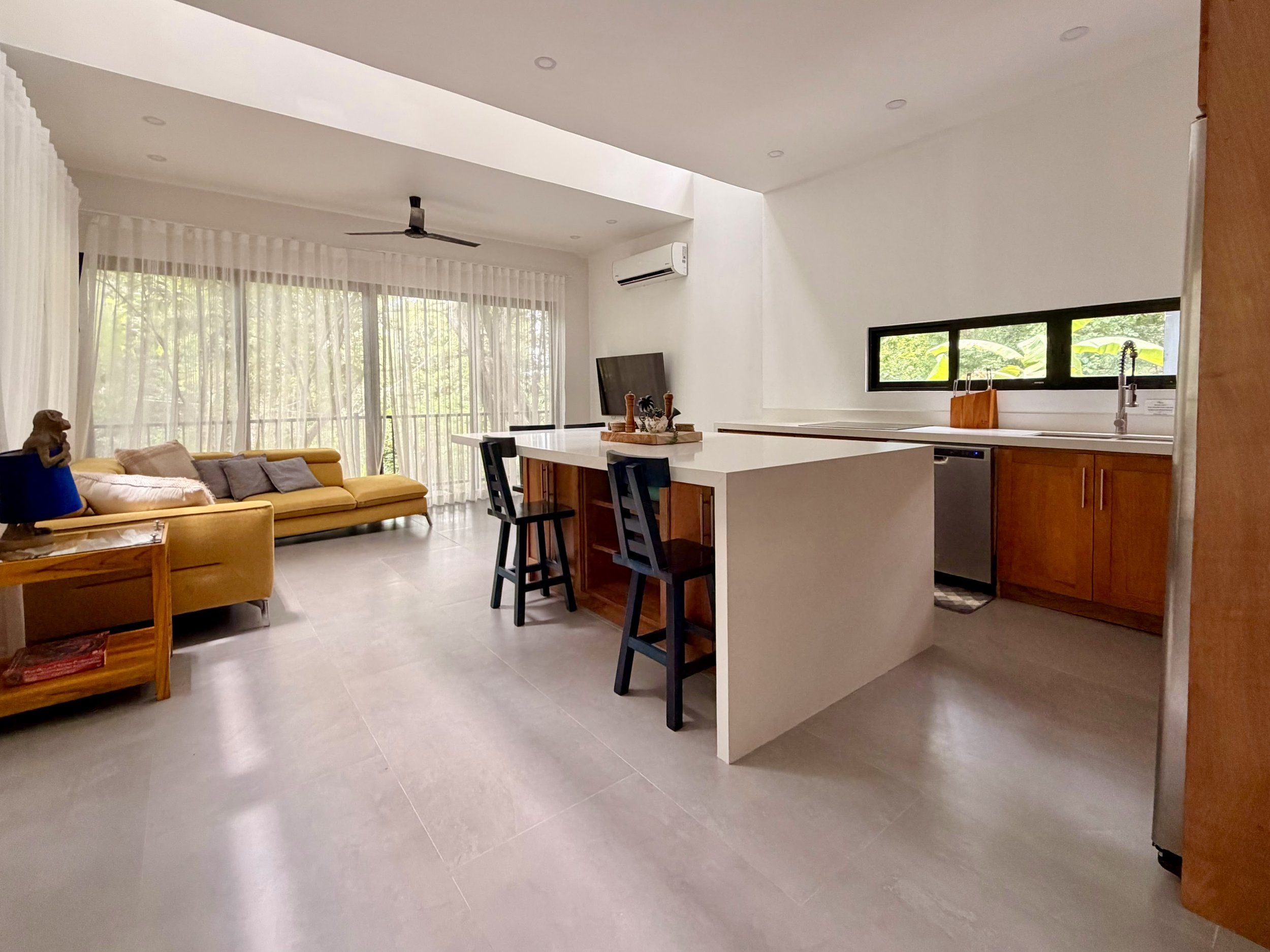 Casa Colina bright open-plan kitchen and living area with white countertops, breakfast bar and natural light.