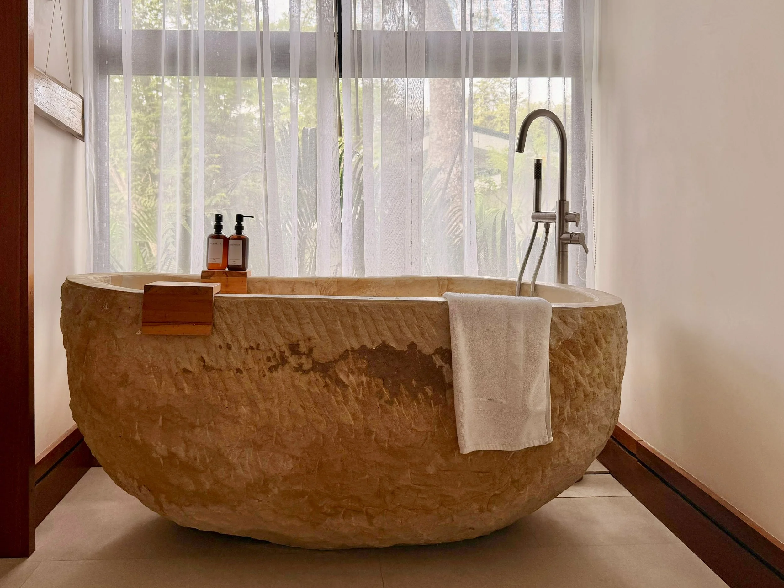 Casa Quantum luxury bathroom featuring a freestanding carved stone bathtub with garden views in Paquera, Costa Rica.