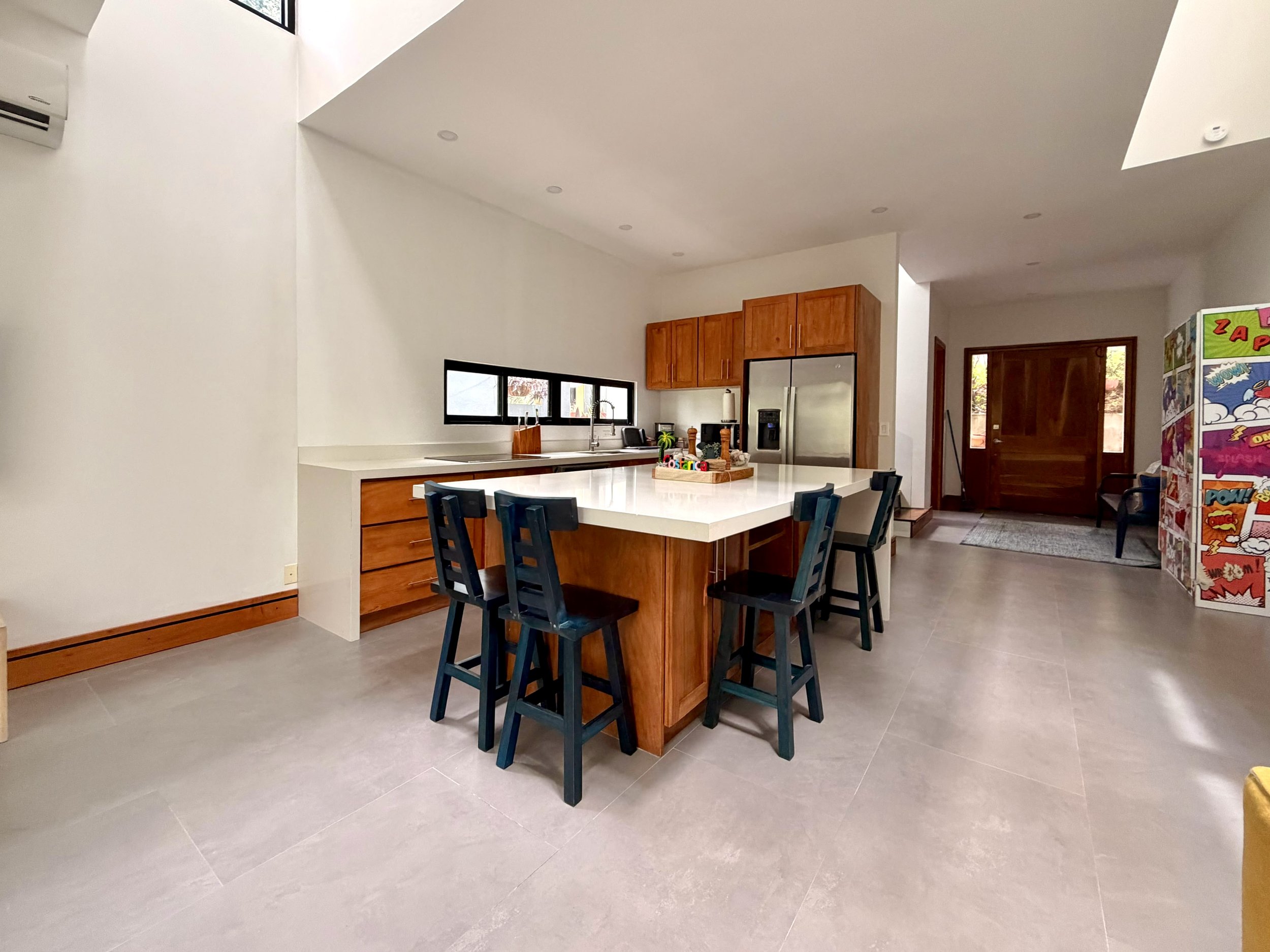 Casa Colina open-concept kitchen with large island, wooden cabinets and contemporary finishes in Paquera, Costa Rica.