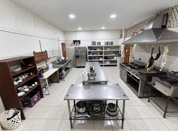 Equipped restaurant kitchen with commercial cooking range, extraction hood and stainless steel workstations.