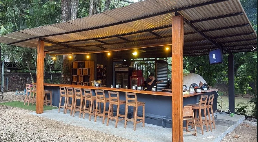 Open-air tropical bar with wooden seating at established restaurant property in Tambor, Costa Rica.