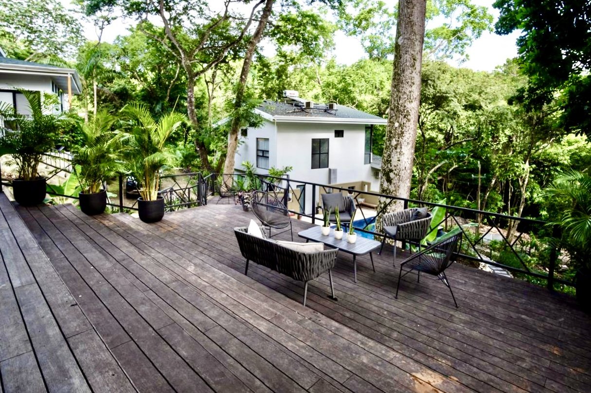 Expansive outdoor wooden deck with lounge seating overlooking lush tropical greenery at House of Light near Playa Órganos, Costa Rica