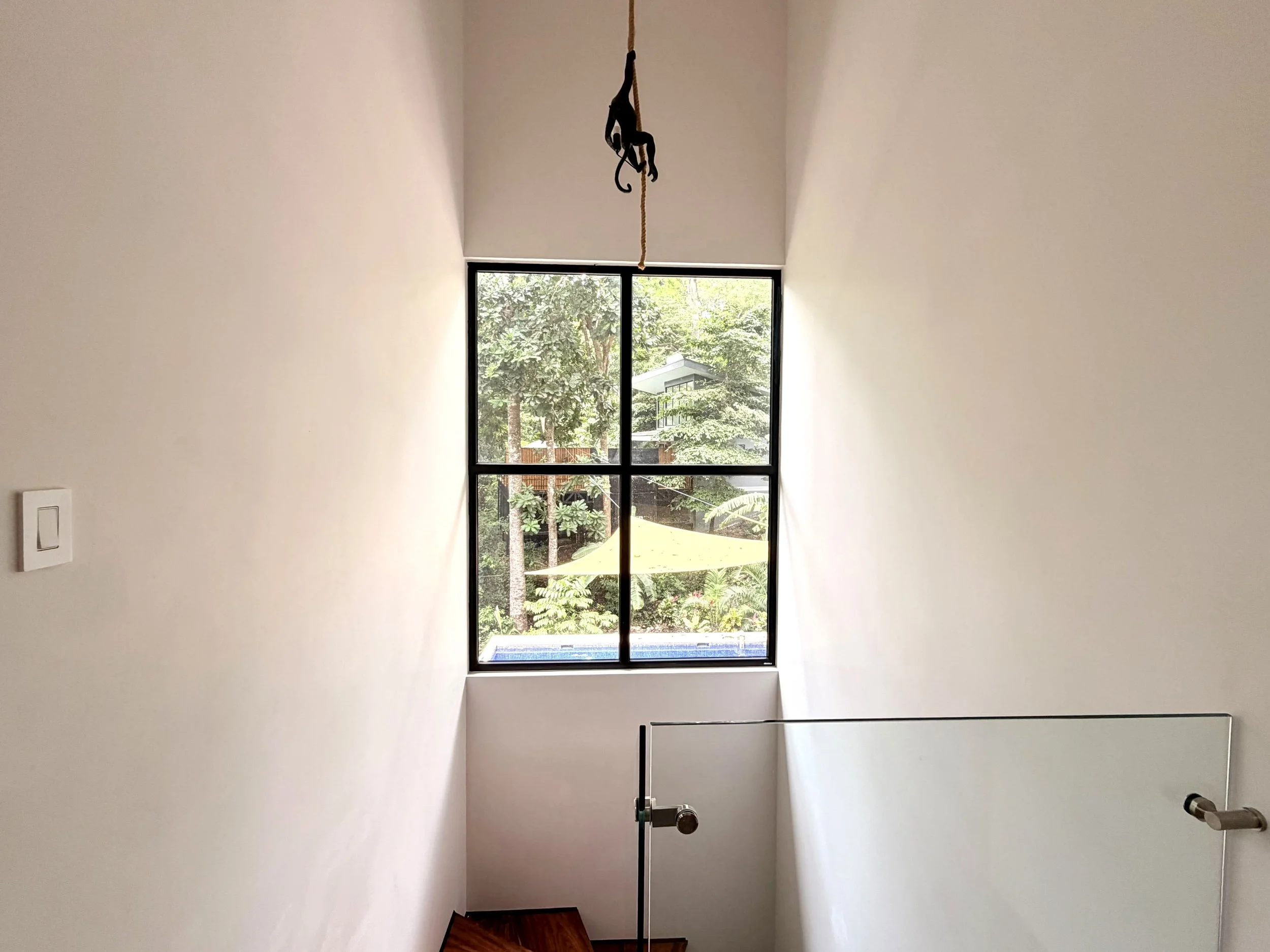 Casa Colina stairwell with large window overlooking lush tropical trees and surrounding greenery.