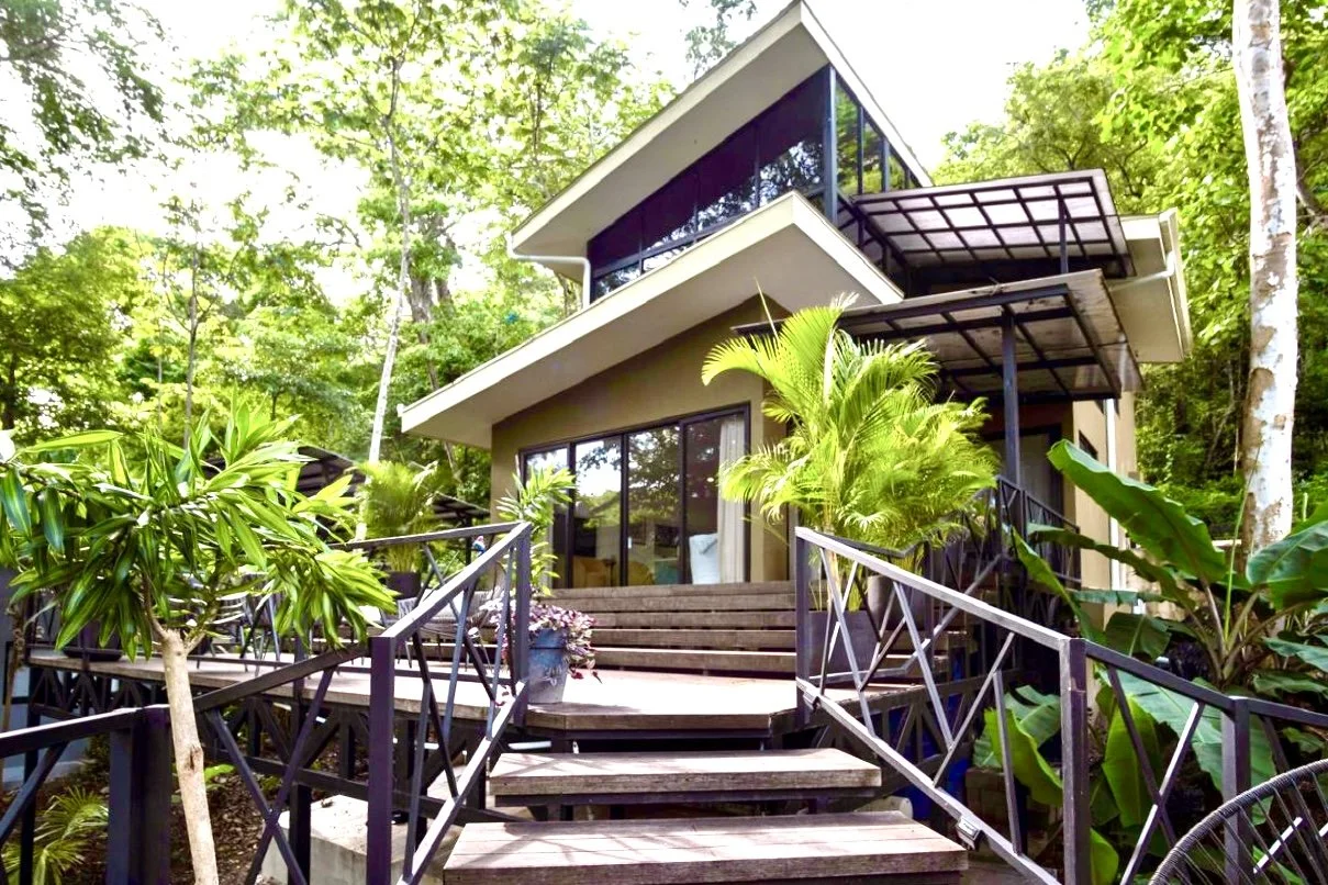 Exterior of House of Light tropical home with elevated wooden entrance and lush gardens near Playa Órganos, Paquera, Costa Rica