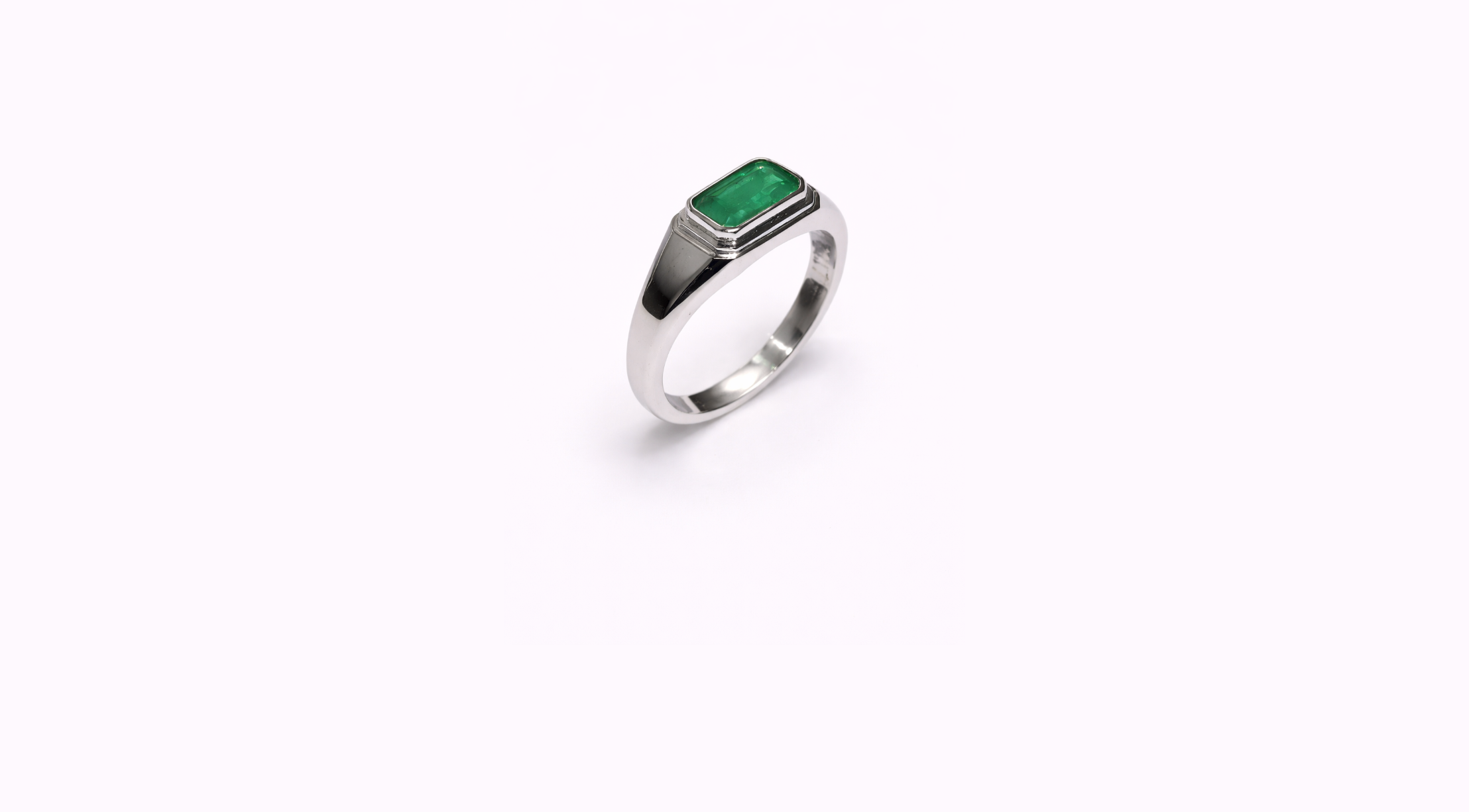 Silver ring with an emerald gemstone on a white background