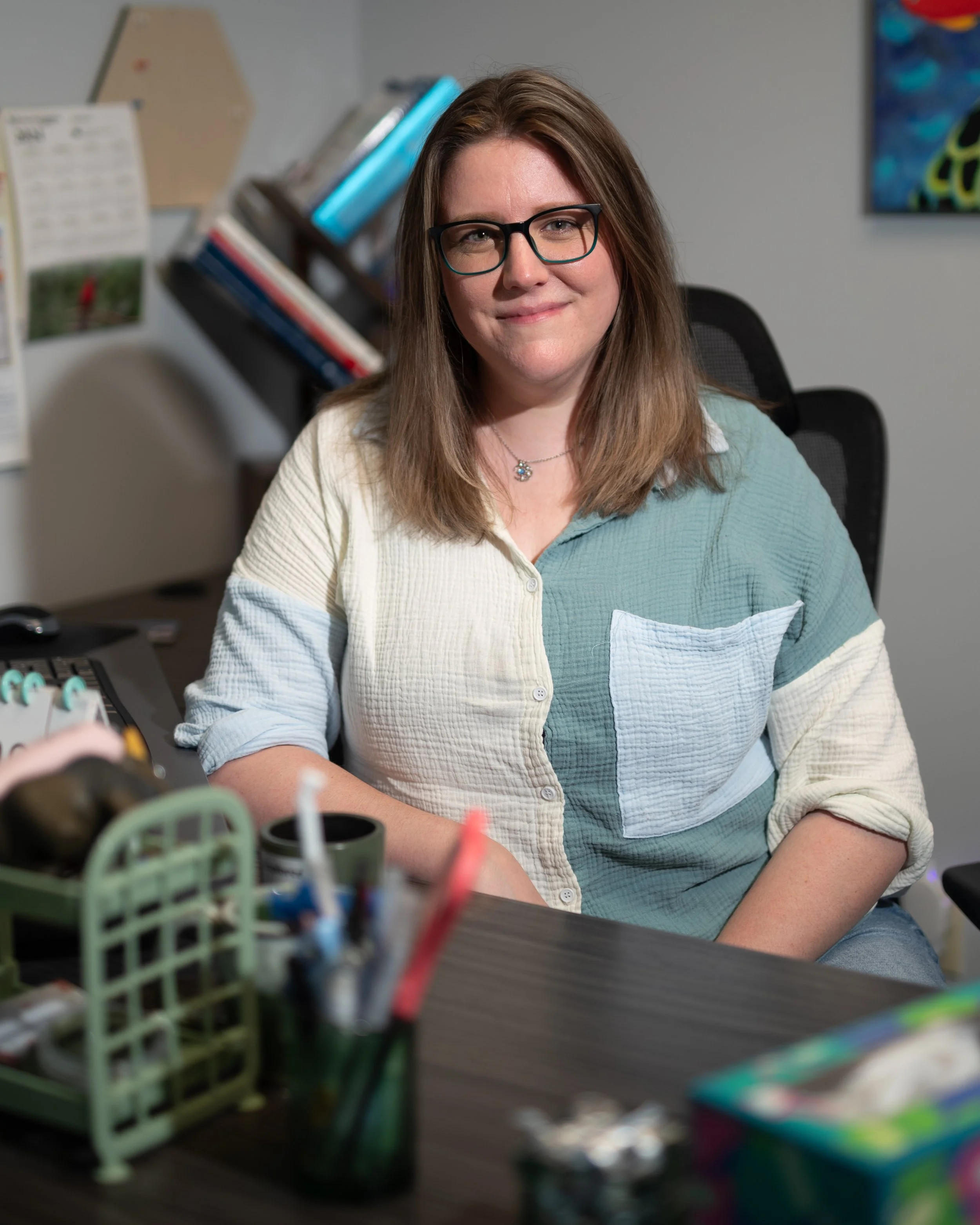 Alyssa Aikman is a friendly looking brown haired woman sitting behind her desk at Kaleidoscope Rx in Vancouver, Washington.