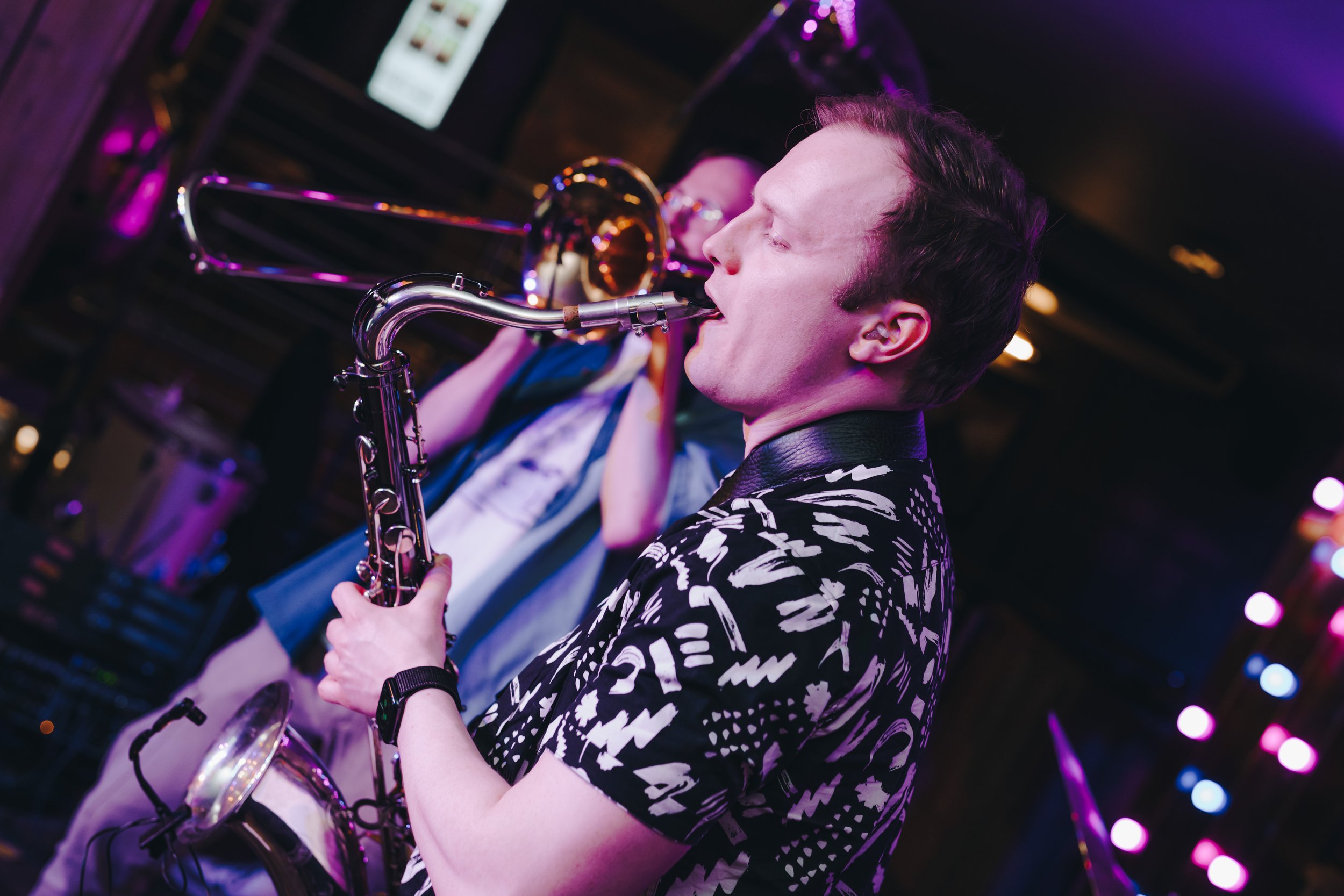 Two musicians performing with a saxophone and trombone on stage.