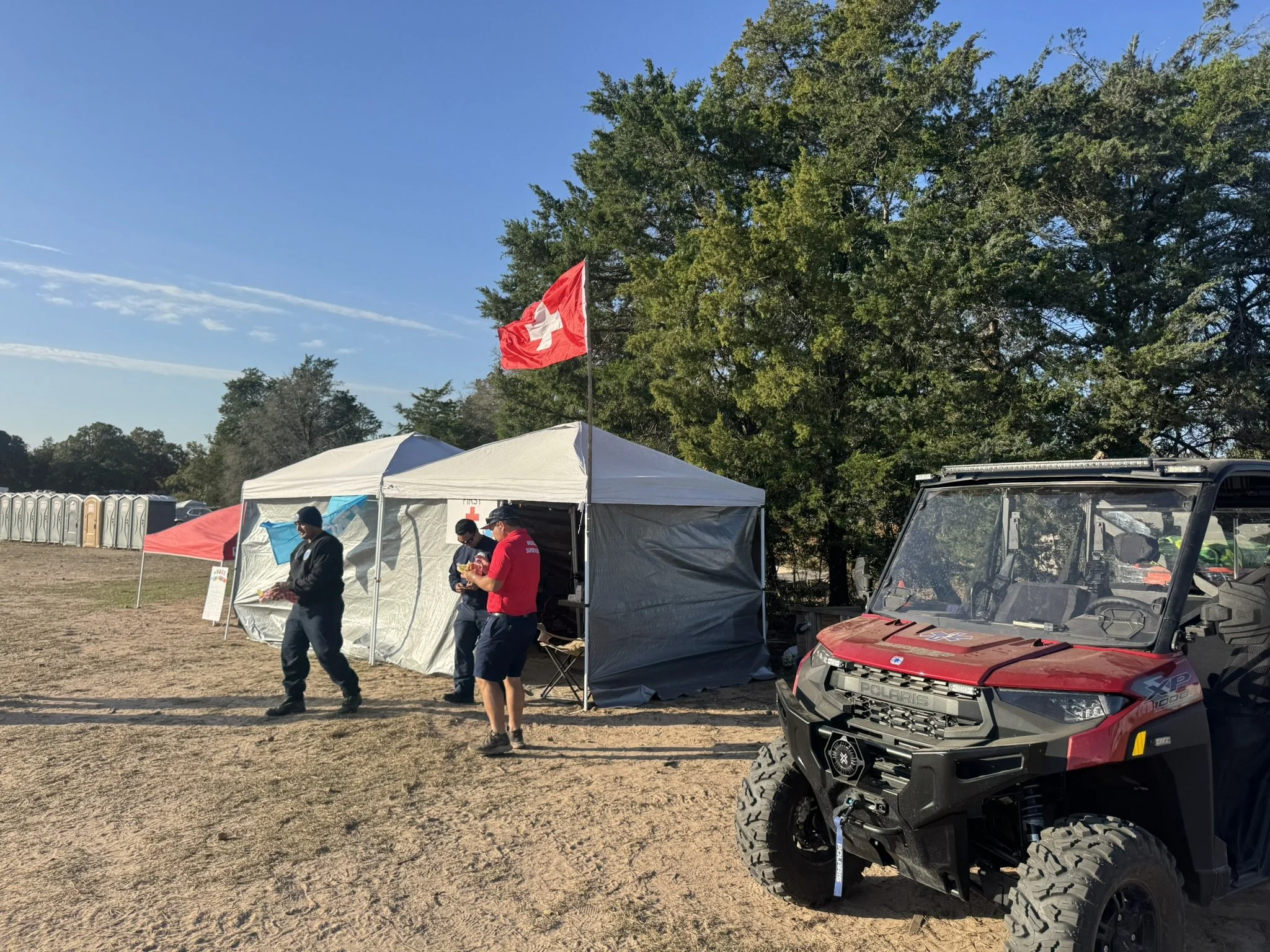 Three on-site EMTs with Bluebonnet Medical Services preparing at a dual medical tent with medical UTV for event medical standby in Central Texas