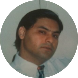 A man with dark hair and light skin wearing a white shirt and tie, looking at the camera in a close-up portrait.