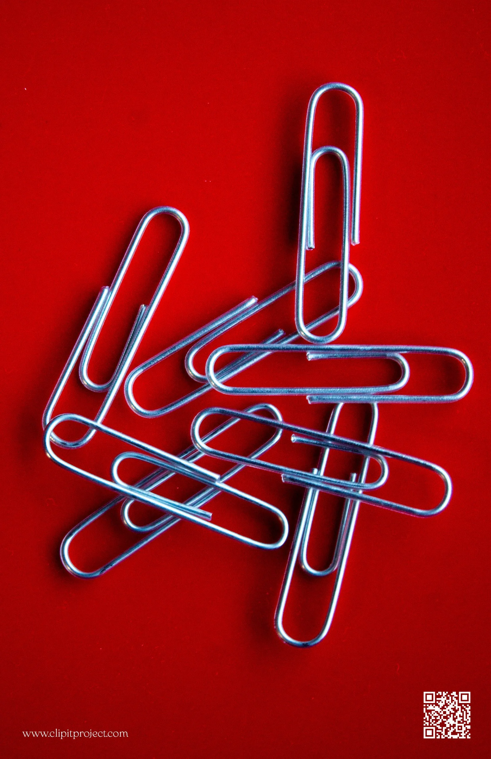 A pile of silver paper clips on a red background.