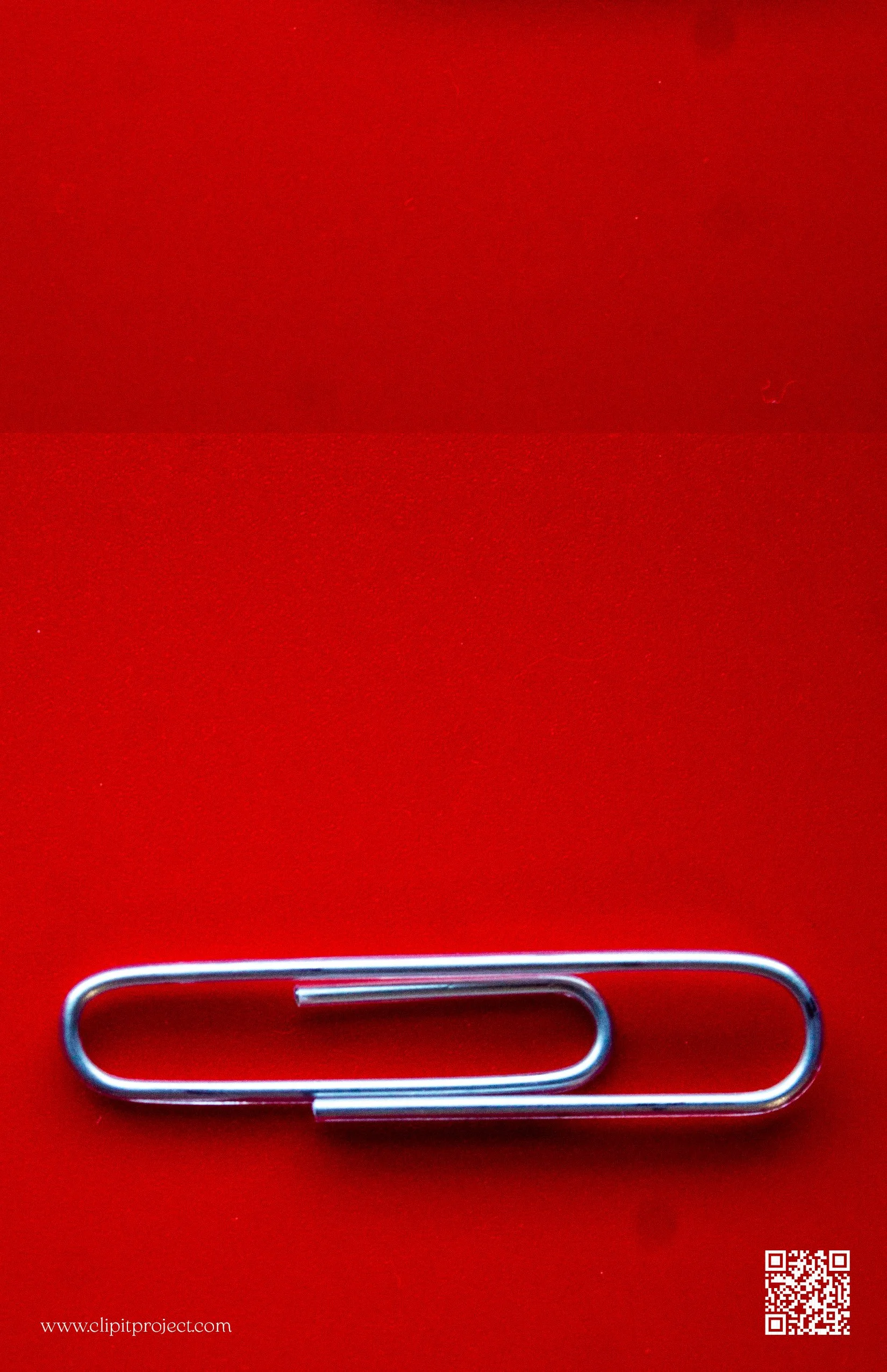 A paperclip on a red surface with a QR code and website URL in the bottom corners.